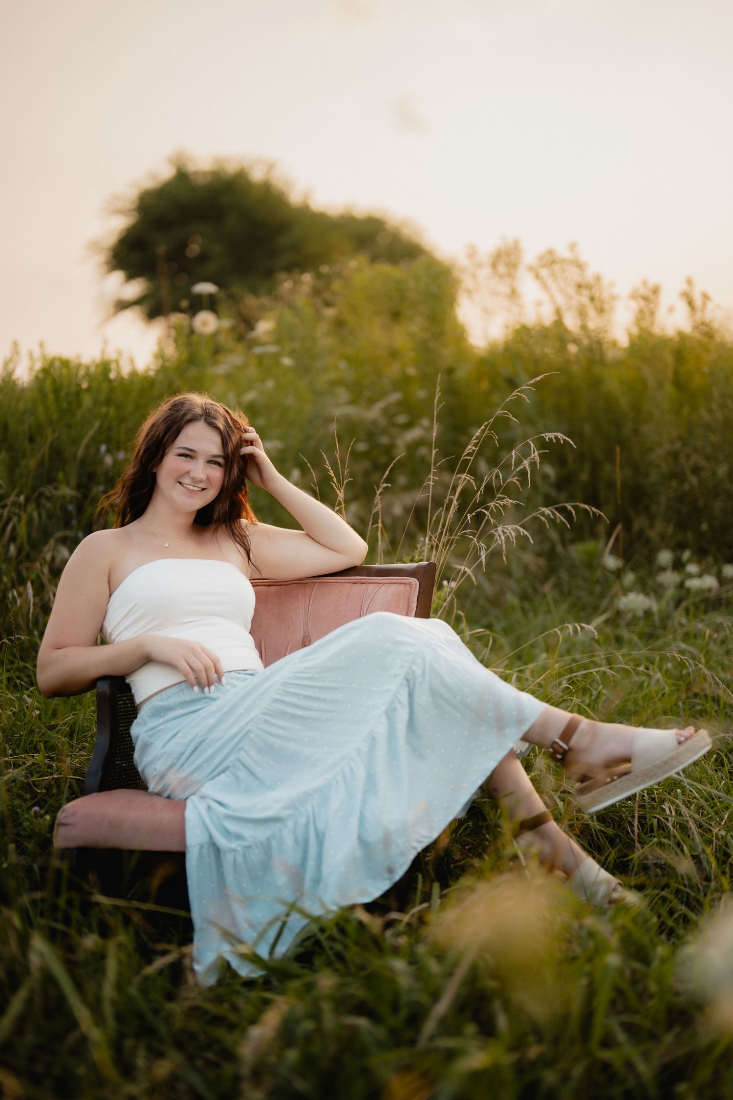 Summer portrait session in white dress laying in tall grass during golden hour. Lindsey ohio Wilson Nature Preserve