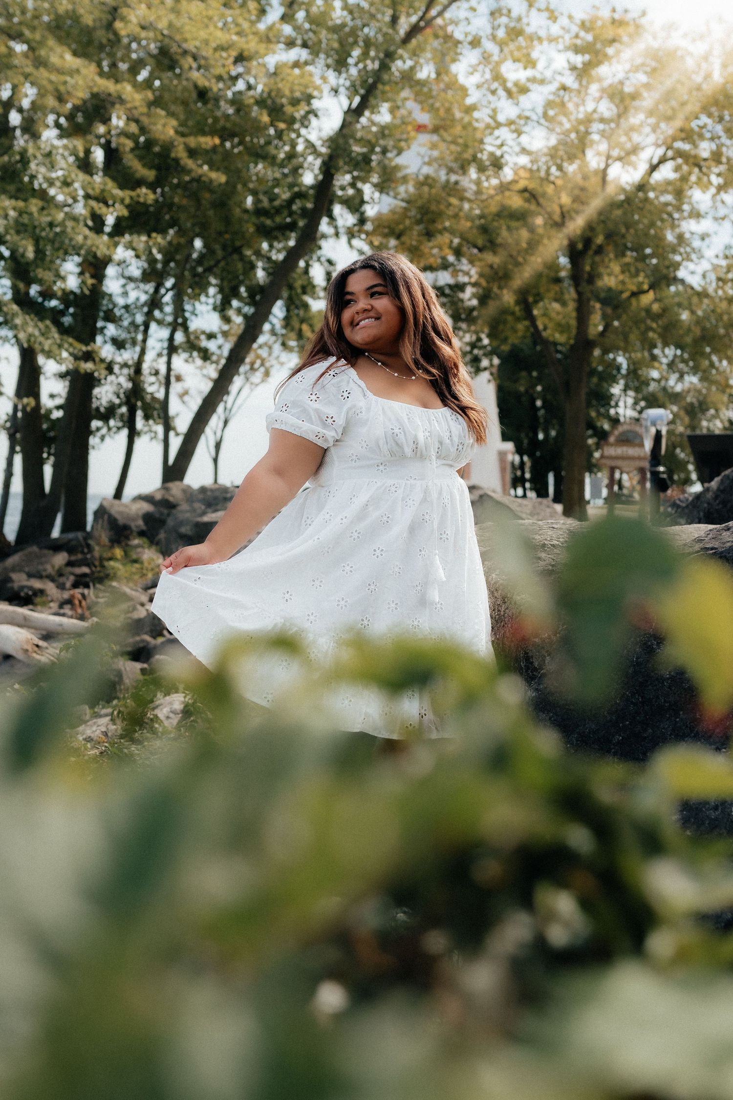 Dreamy outdoor portrait in white dress with sunlit trees in background. Marblehead Lighthouse Ohio