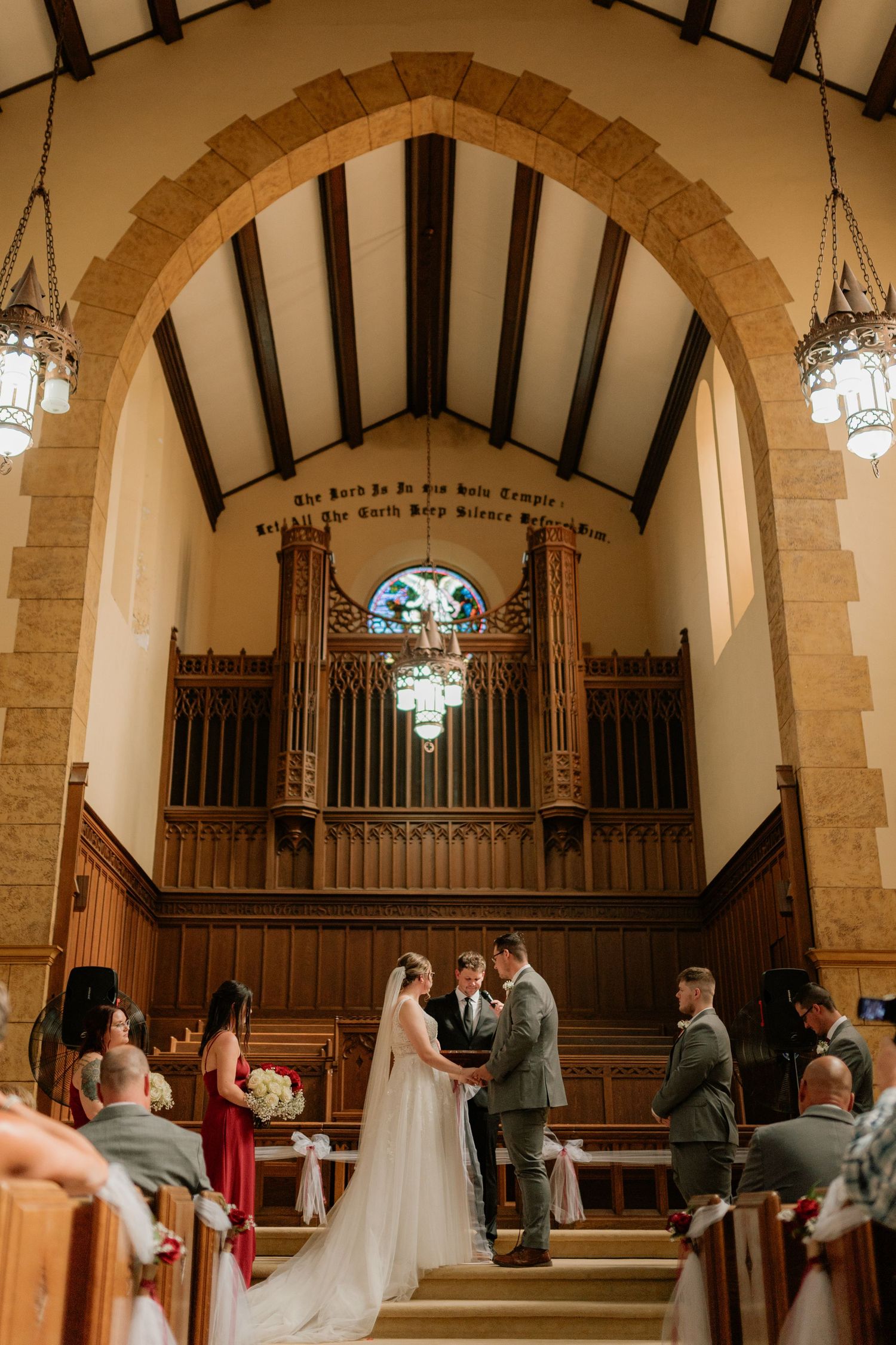 A beautiful church wedding ceremony with wooden pews and an ornate pipe organ backdrop. Tiffin, Ohio Wedding Venue