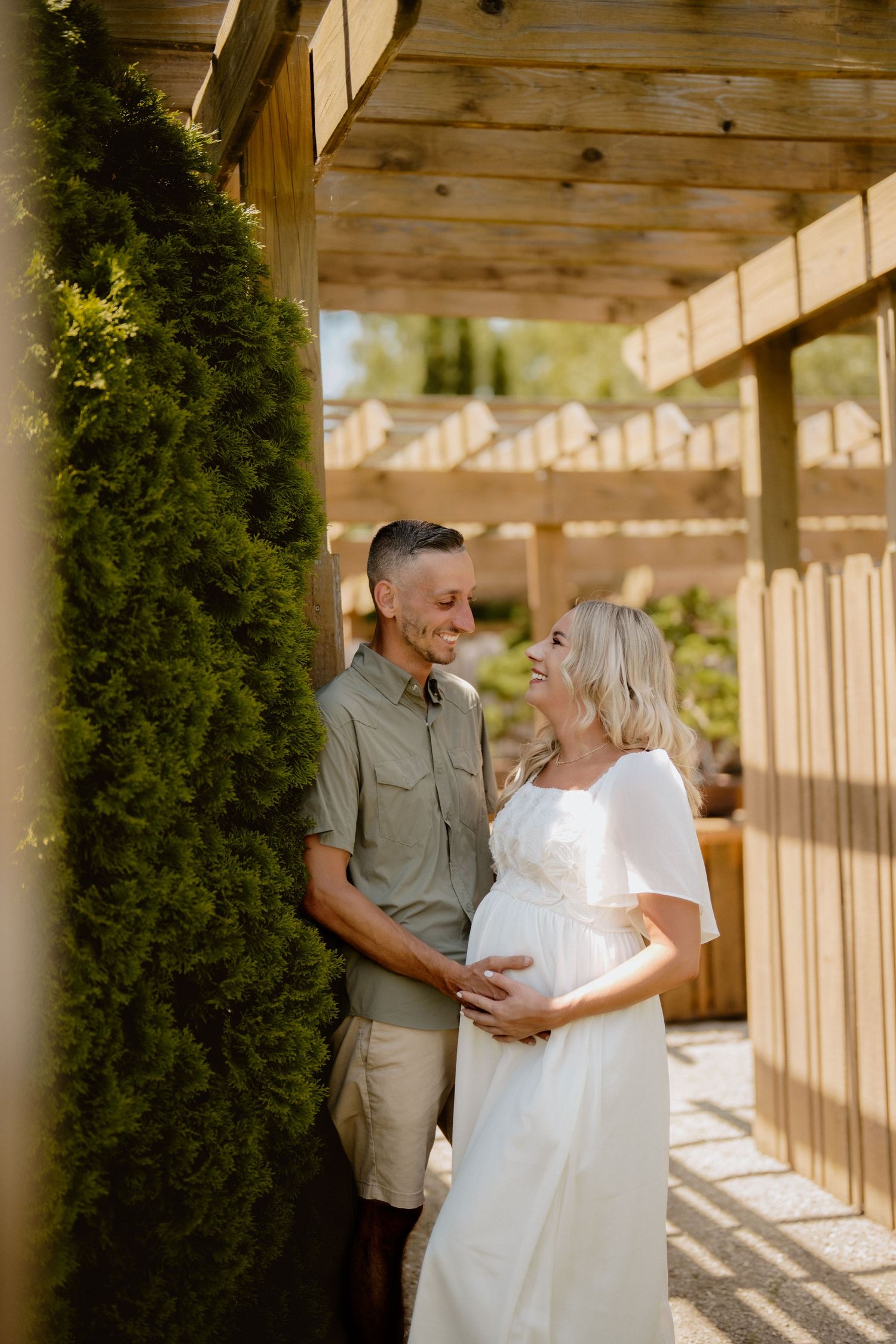 A tender maternity moment captured under a wooden pergola with green foliage. Schedel Gardens, Elmore, Ohio