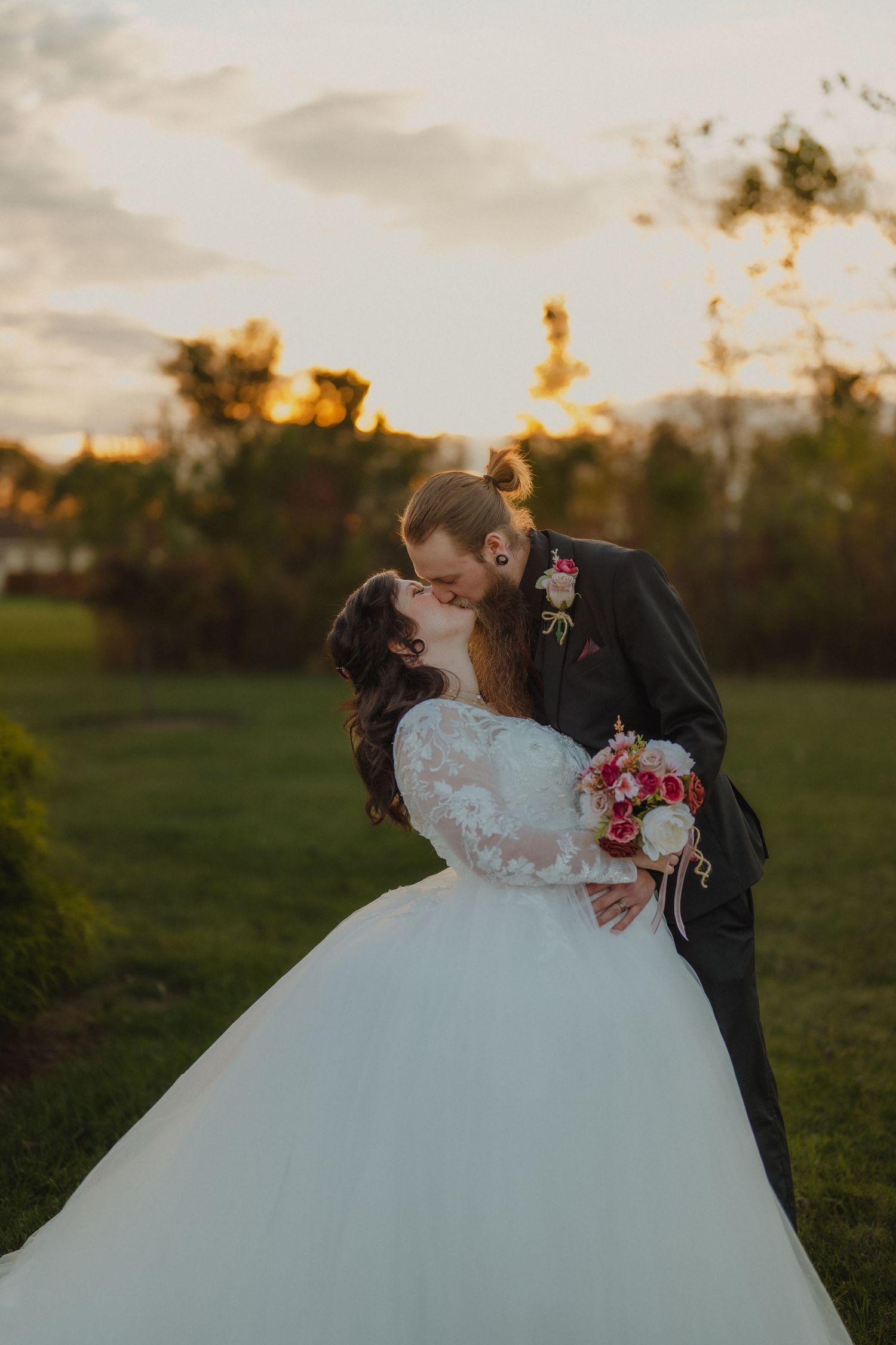 A romantic sunset wedding photo showing a couple in a grassy field with warm glowing light. Helena, Ohio