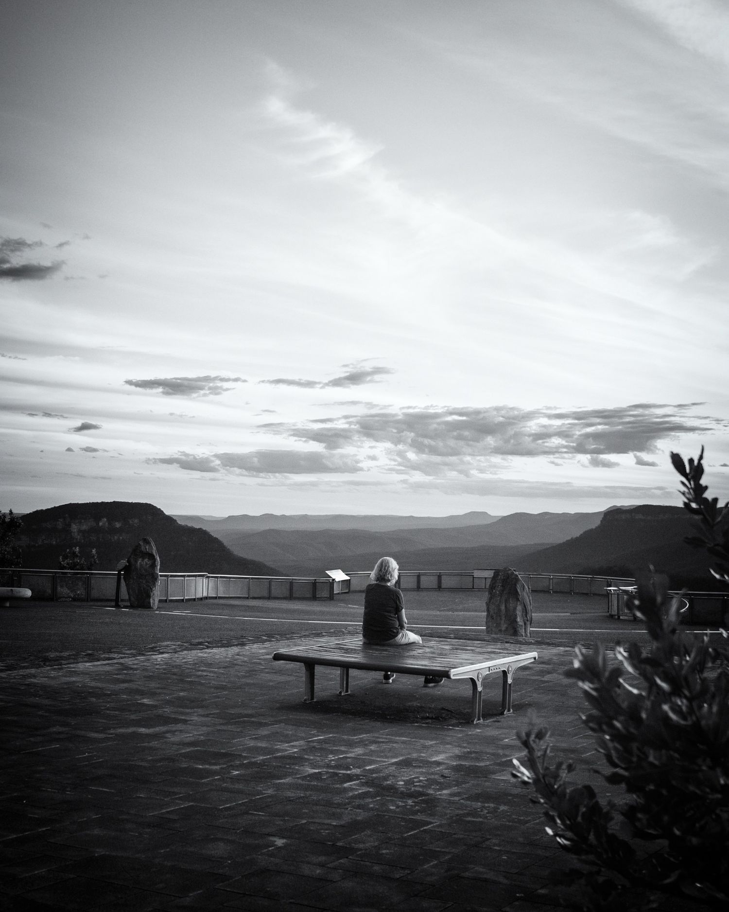 Silhouettes against a mountain backdrop at sunset create a peaceful monochrome scene.