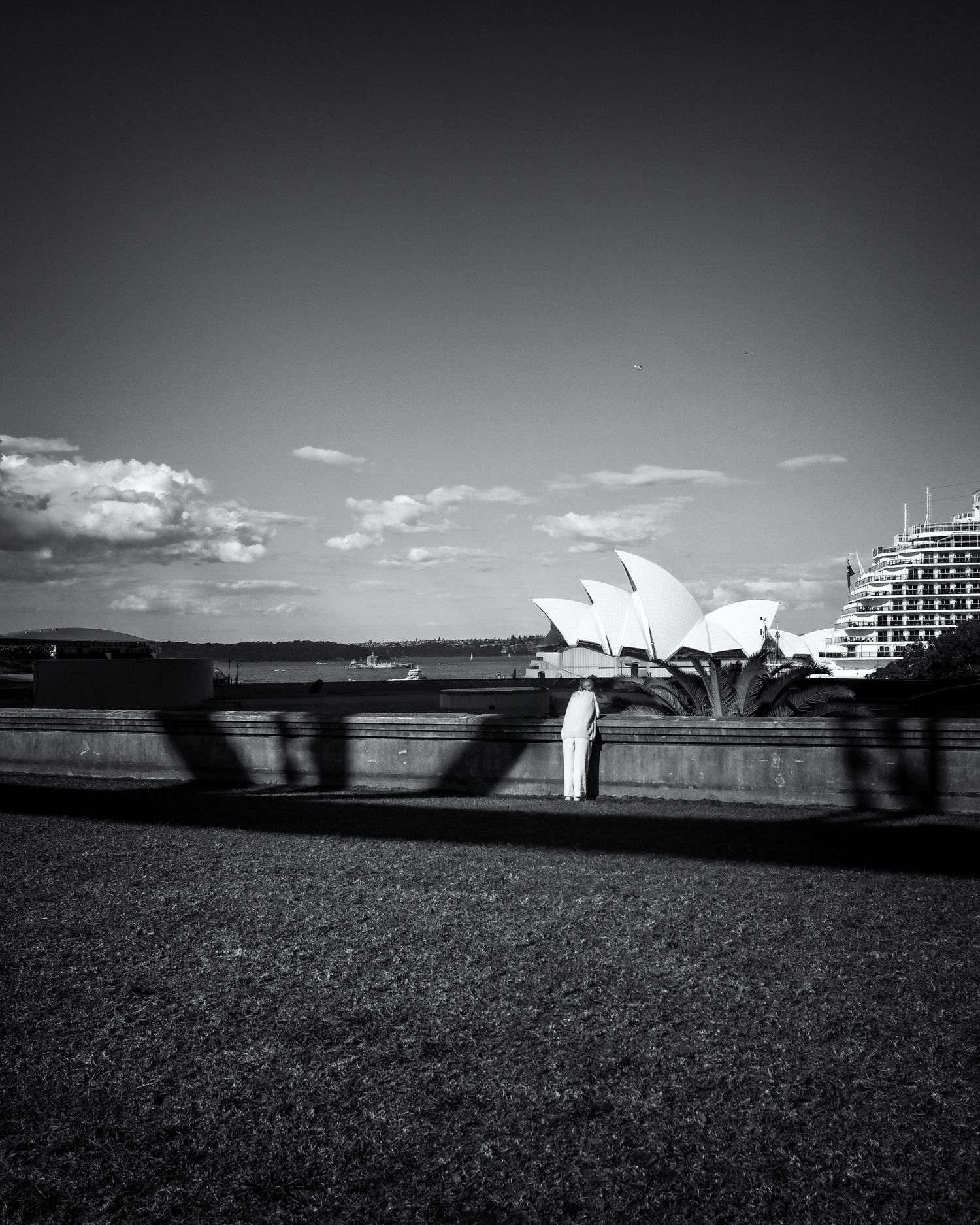 Black and white photo of Sydney Opera House with dramatic shadows and clouds in the background.