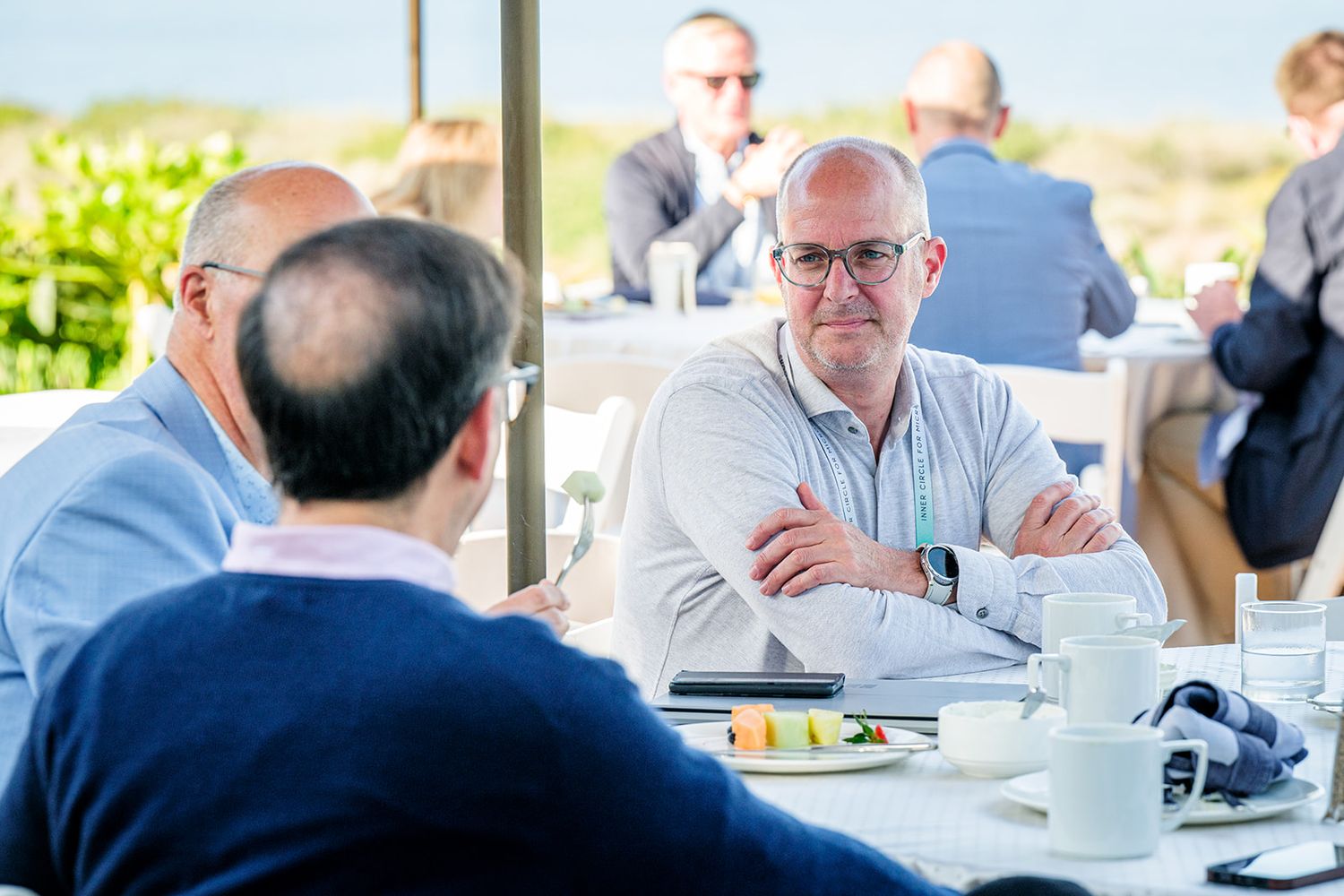 Business professionals seated at round tables during a corporate event.