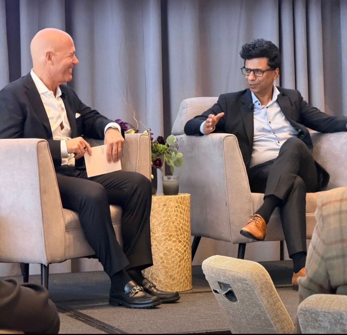 Business meeting setup with gray armchairs arranged for panel discussion.