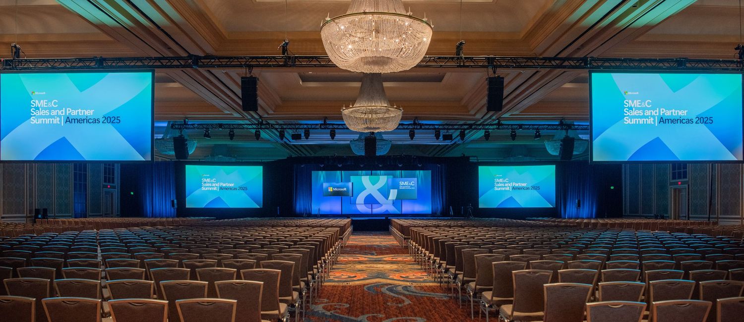 Conference hall with blue lighting and digital displays set up for corporate presentation.