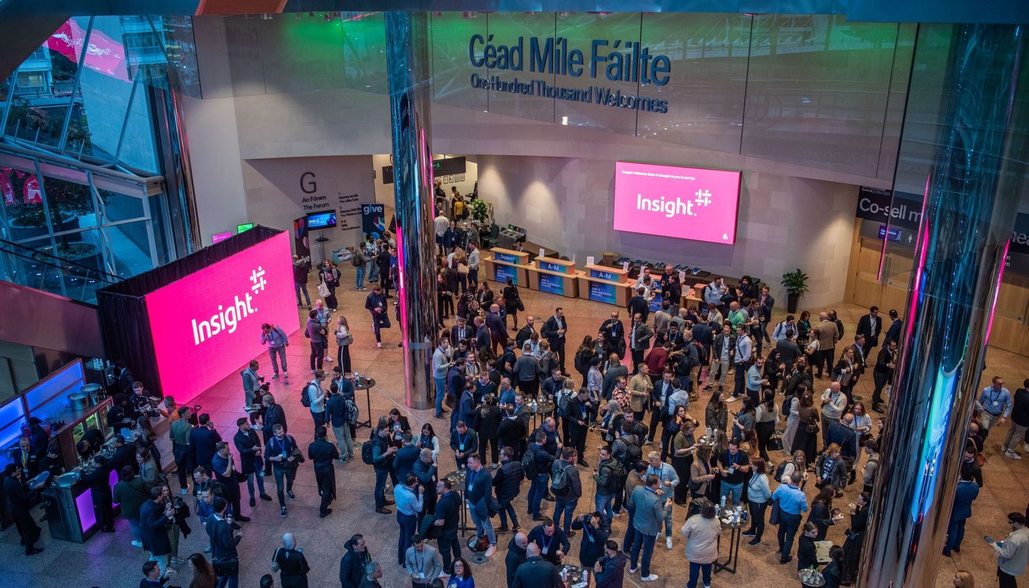 Crowded networking event space with pink lighting and large group of attendees.
