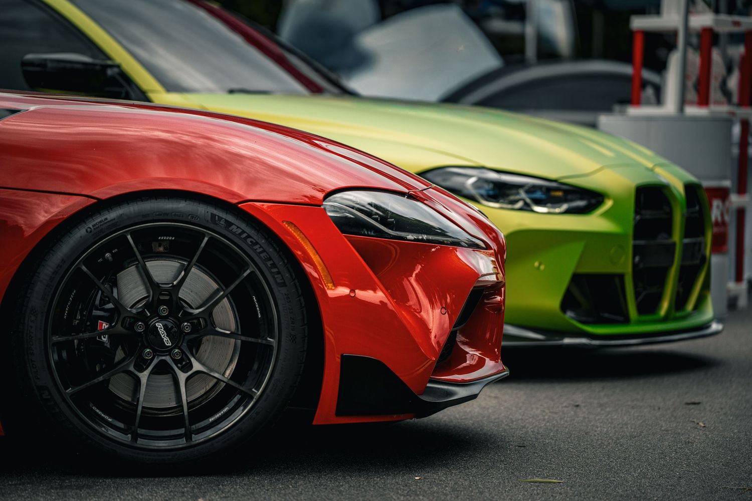 Close-up view of luxury sports car front ends showing colorful paint and black wheels.