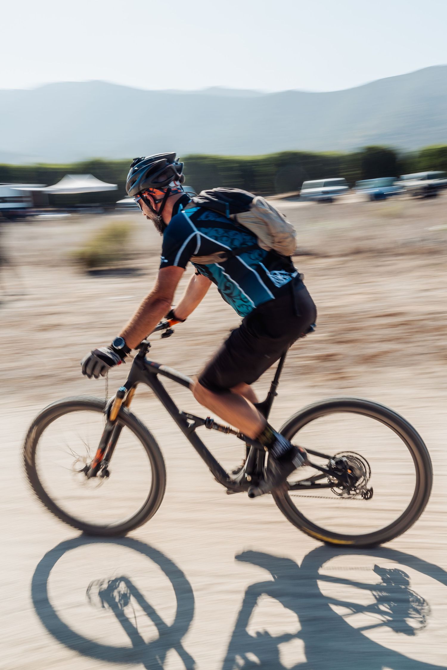 Mountain biker rides through desert terrain with motion blur effect against mountain backdrop.
