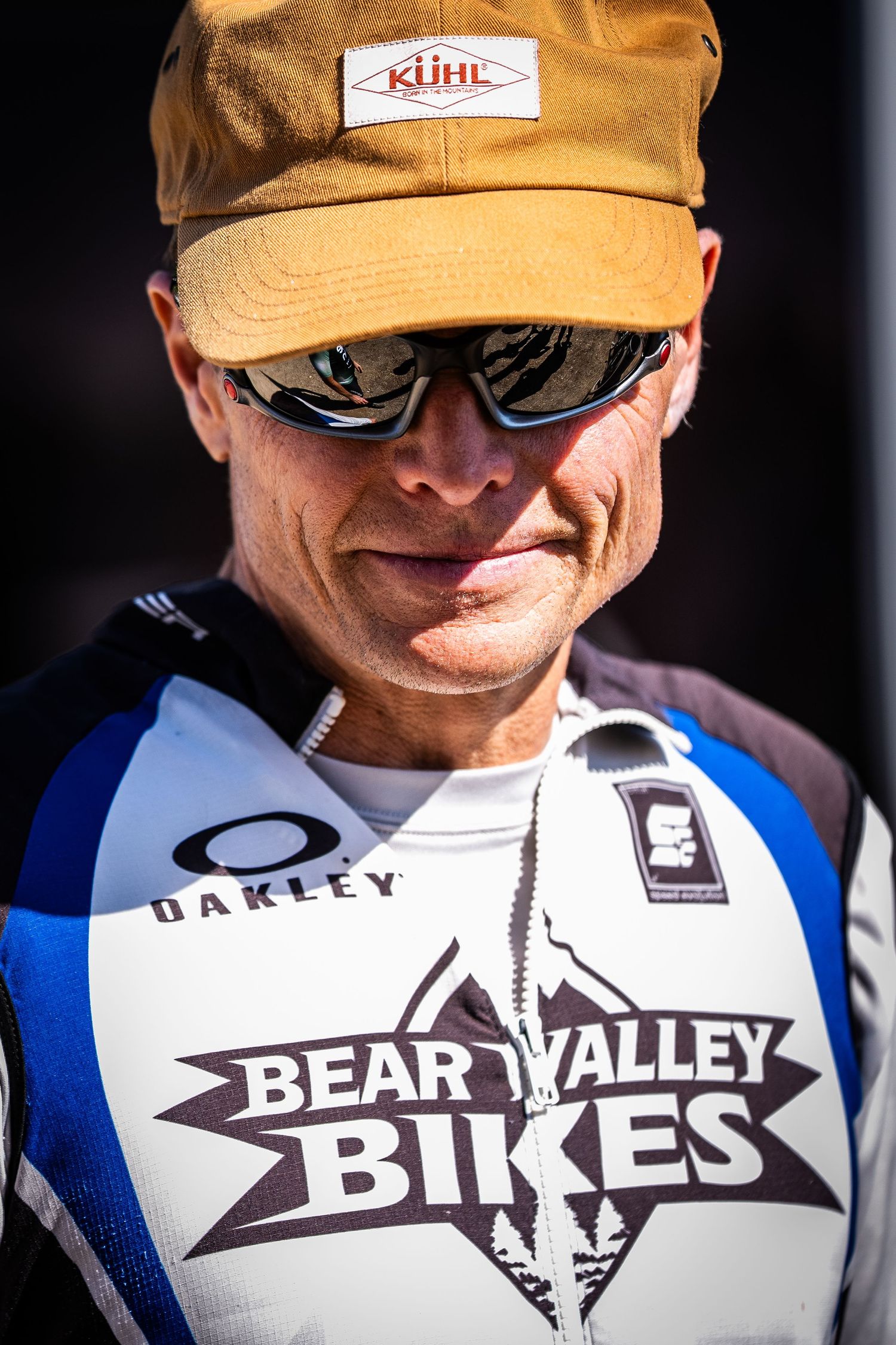 Close-up of athlete wearing yellow cap and Bear Valley Bikes racing jersey.