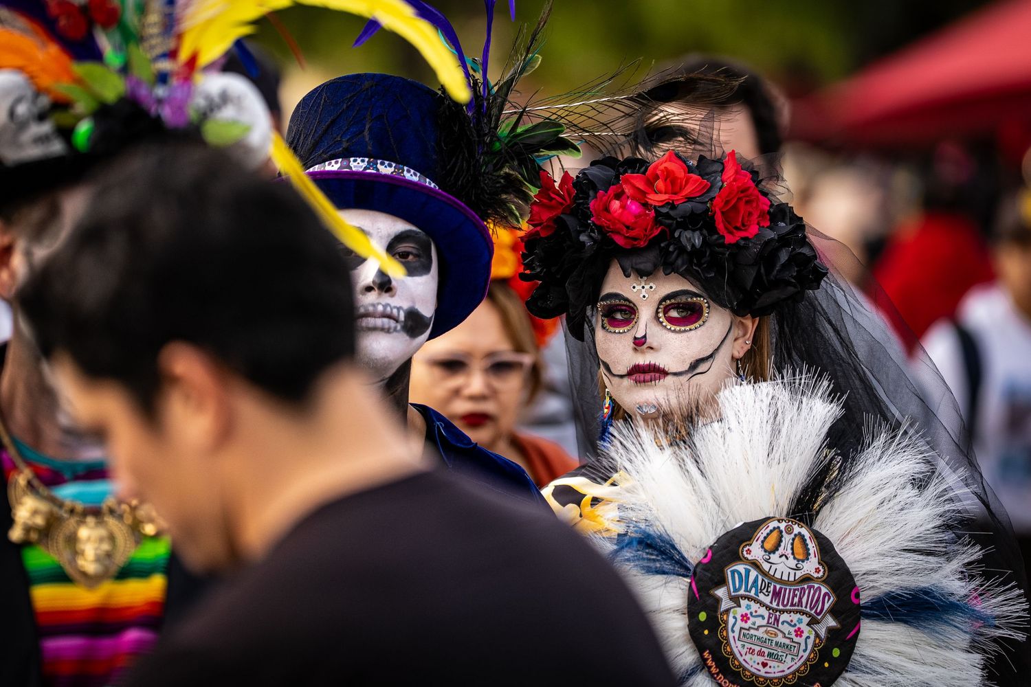 Colorful Day of the Dead festival celebration featuring elaborate sugar skull makeup and floral headdresses.
