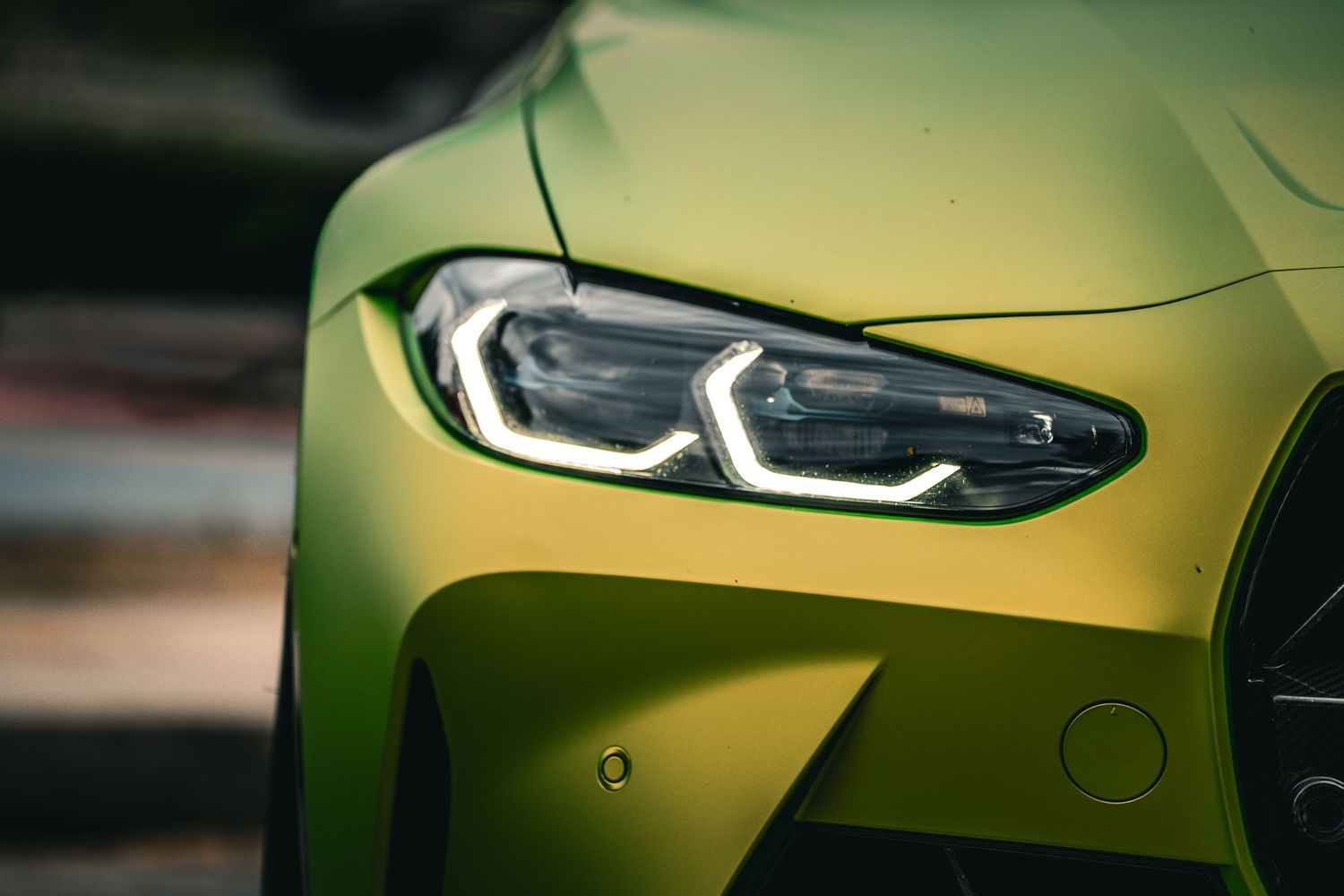 Close-up details of modern luxury car headlights in metallic green finish.
