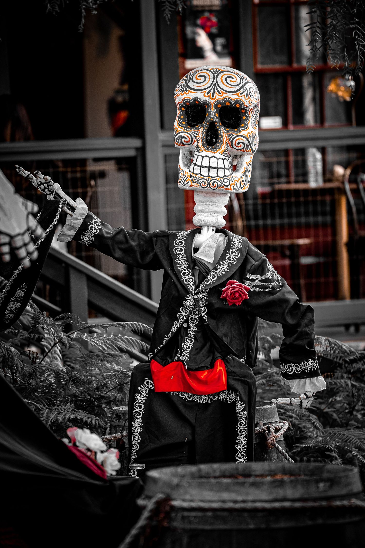 Selective color photo of Day of the Dead decorations with black and red skeleton figures.