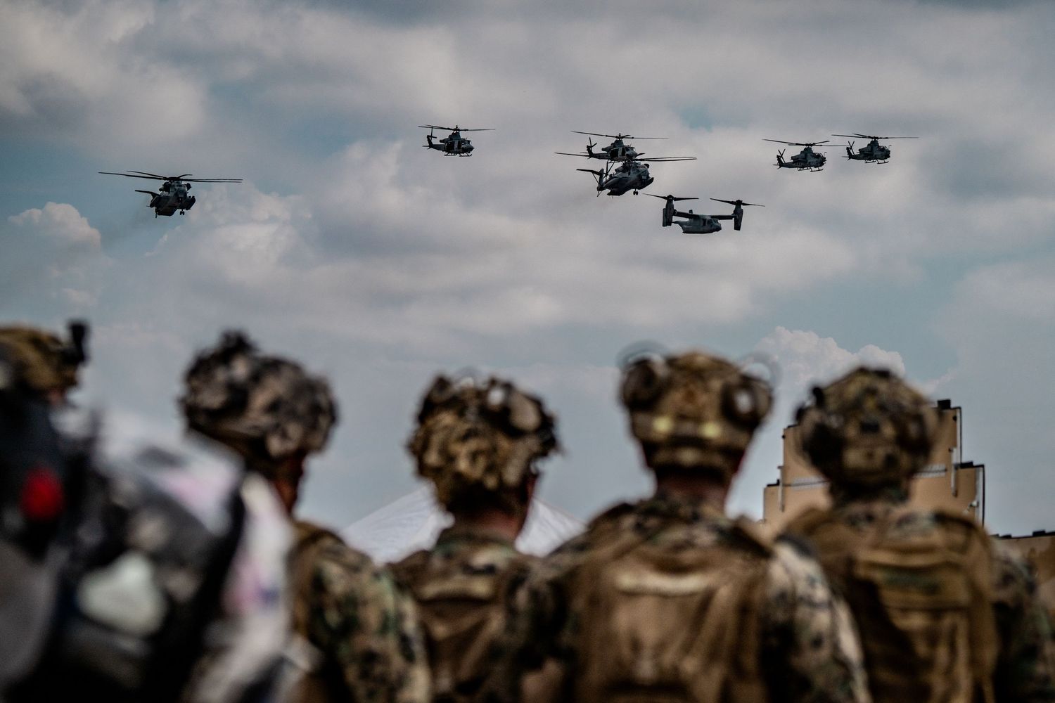 Military helicopters fly in formation against a cloudy sky during a training exercise or operation.