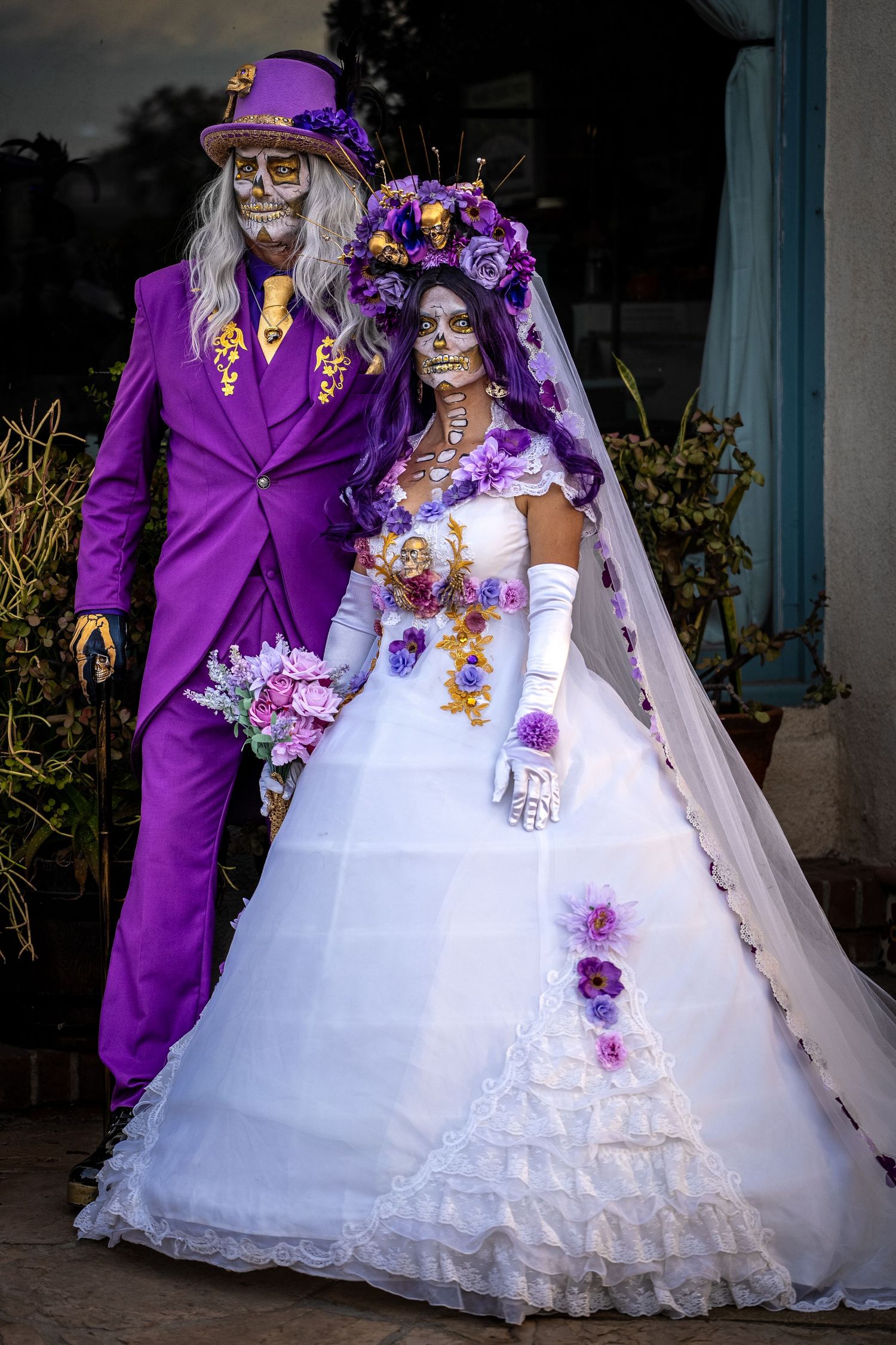 Day of the Dead themed wedding with couple in purple and white attire with sugar skull makeup.
