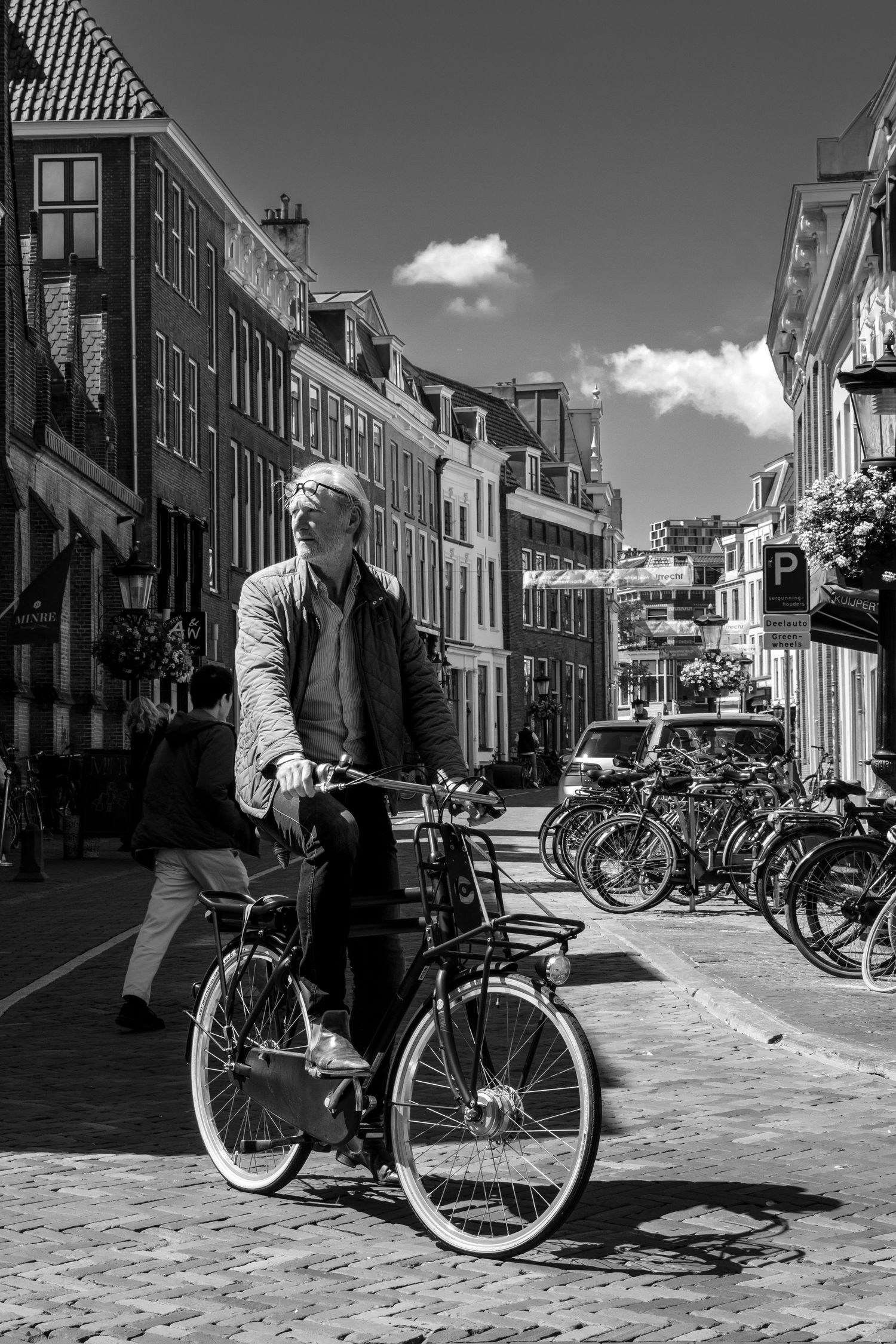 Black and white street scene with bicycles parked along historic European buildings.