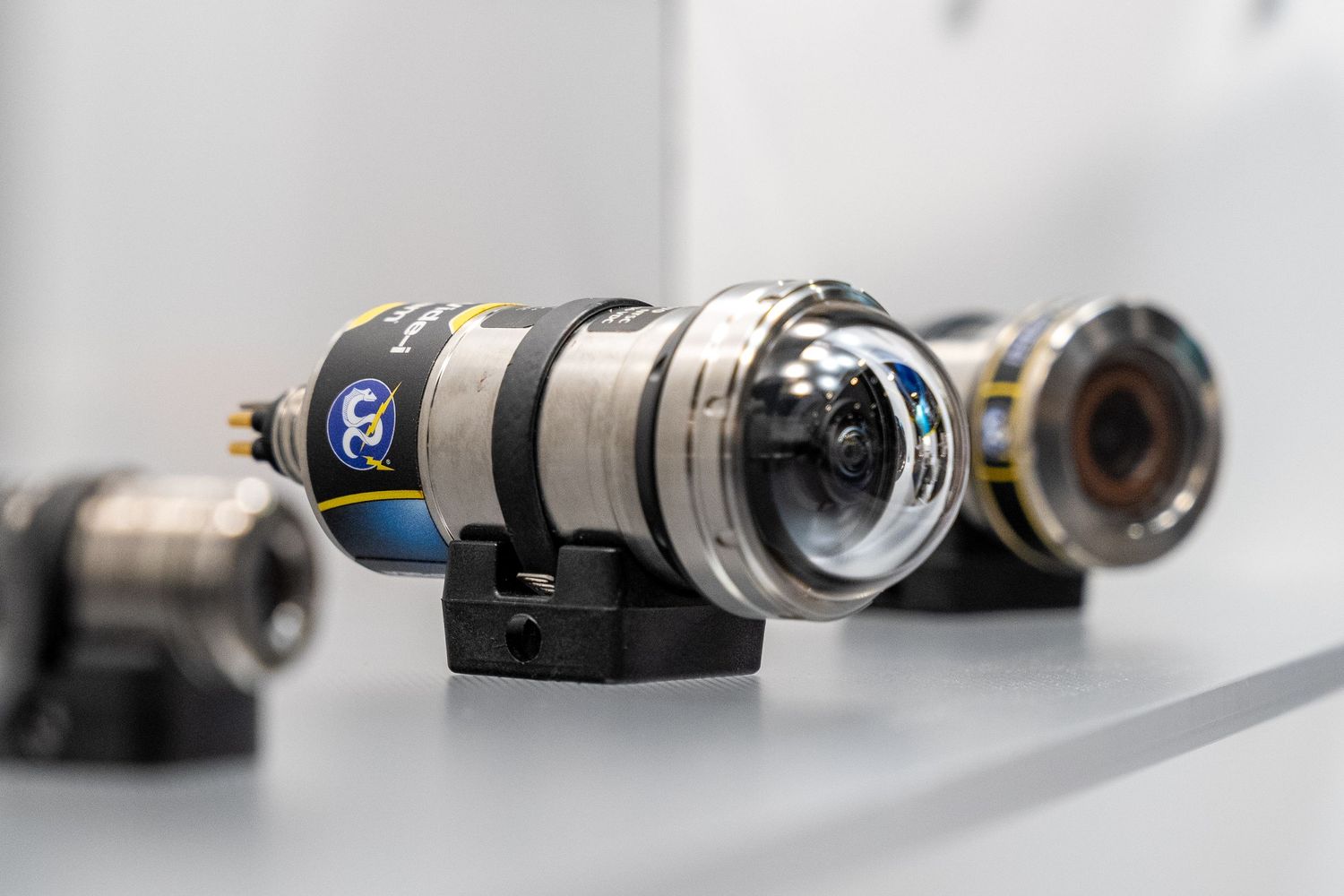 Close-up of industrial underwater camera equipment with chrome lens housing mounted on a display surface.