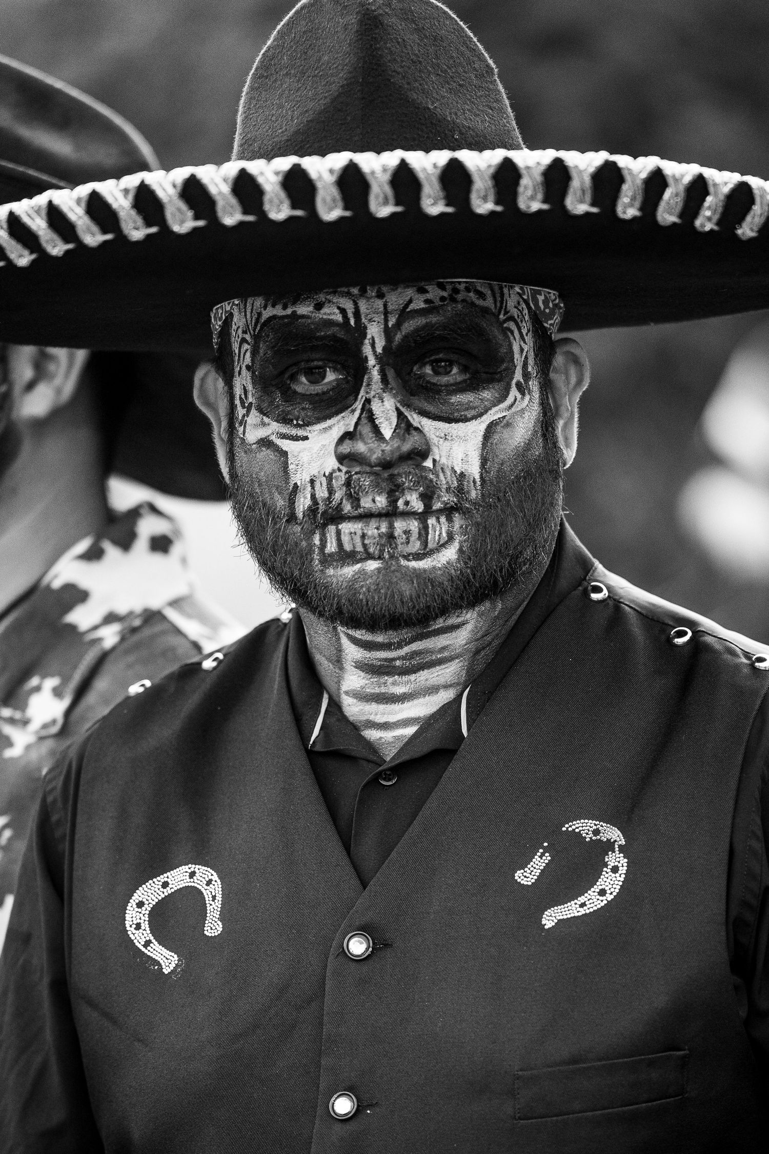 Black and white portrait of performers wearing traditional Dia de los Muertos skull makeup and sombreros.