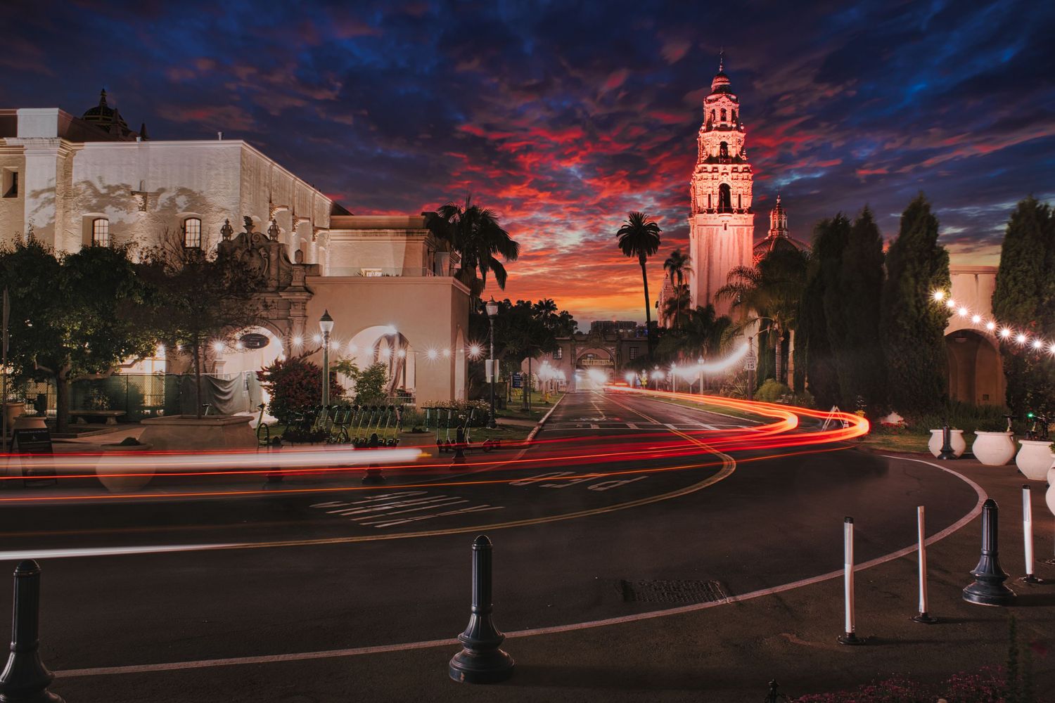 Dramatic cityscape panorama at dusk with light trails and illuminated buildings under colorful clouds.