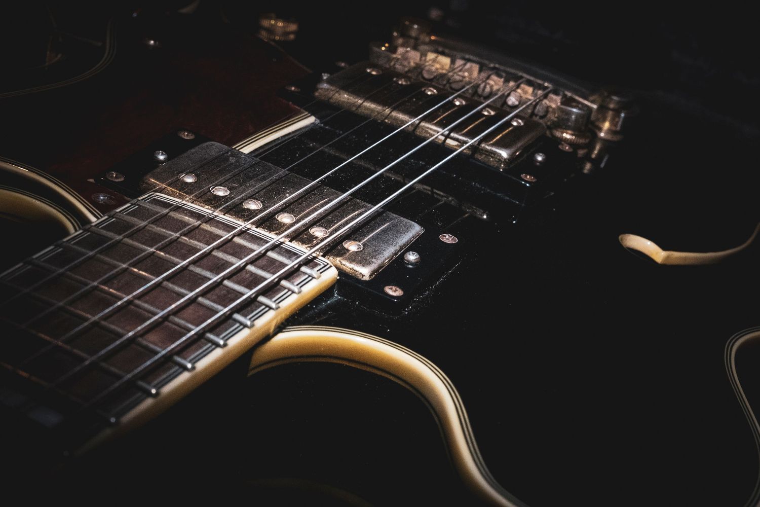Close-up macro shots of an electric guitar showing fretboard, strings, and hardware details in dramatic lighting.