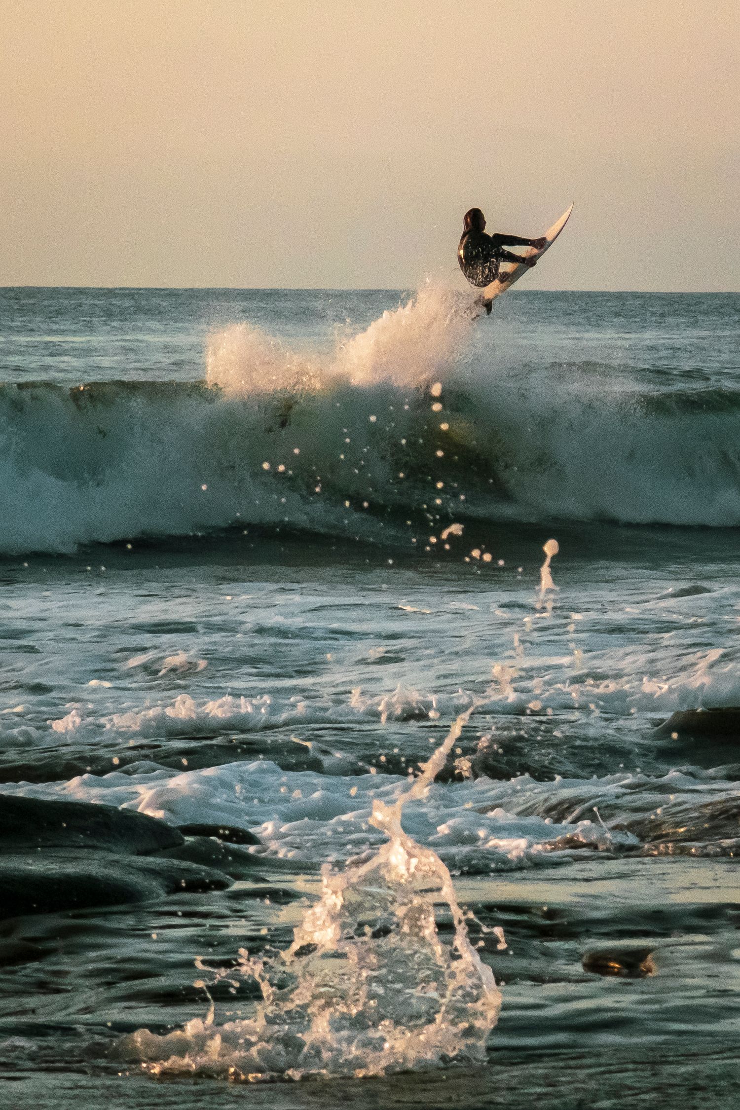 Dynamic sequence of a surfer riding waves with dramatic water splashes at sunset.