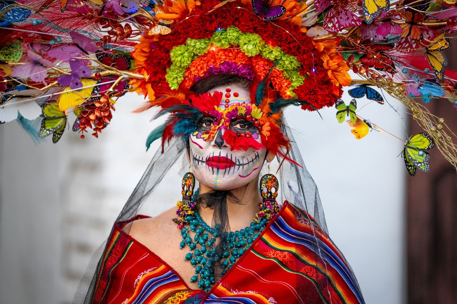 Vibrant floral headdresses and face paint at Day of the Dead celebration with bright colors.