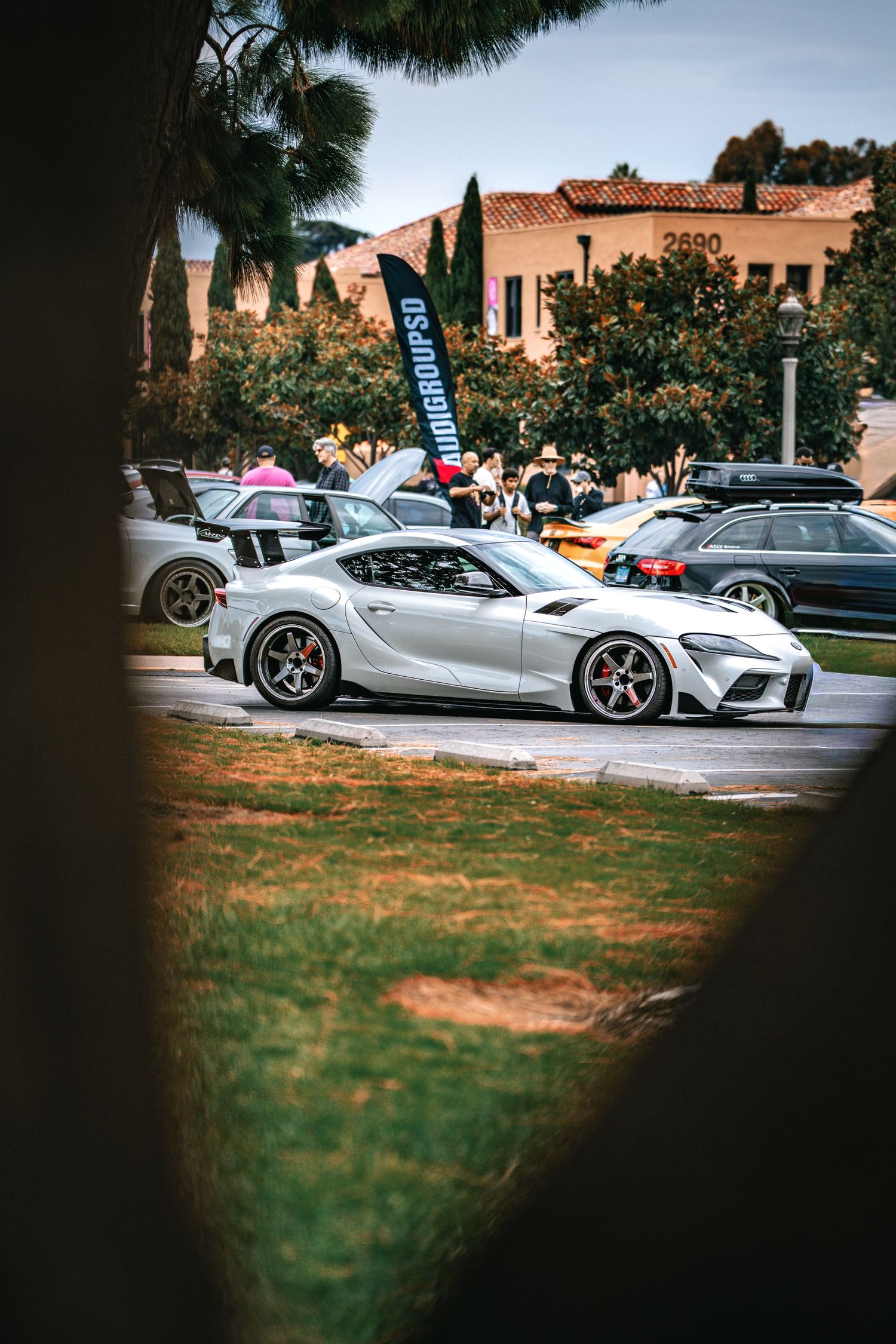 Modern luxury sports cars including McLarens and Ferraris displayed on grass at an outdoor car show.