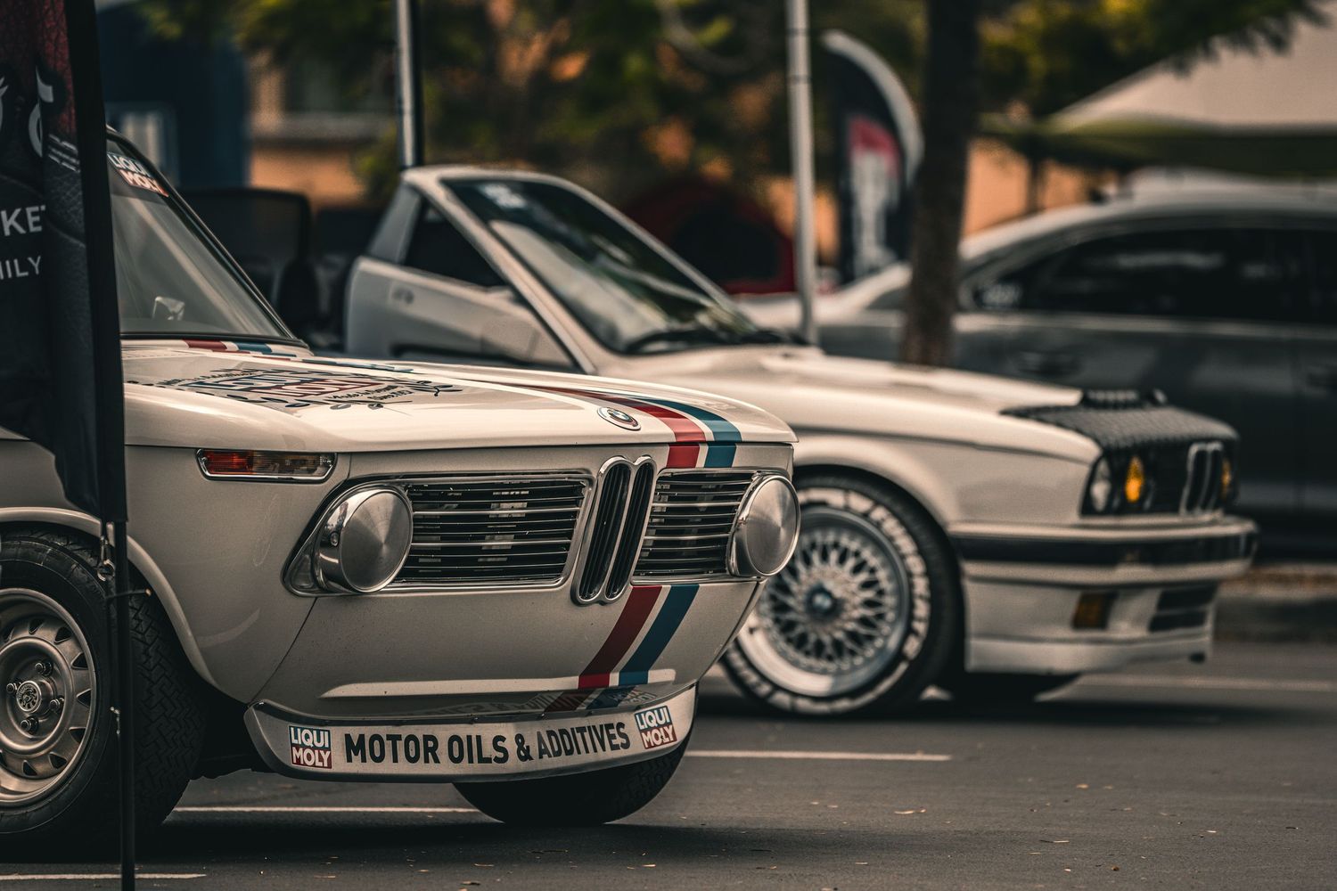 Row of classic cars showcasing their polished chrome bumpers and vintage styling details.