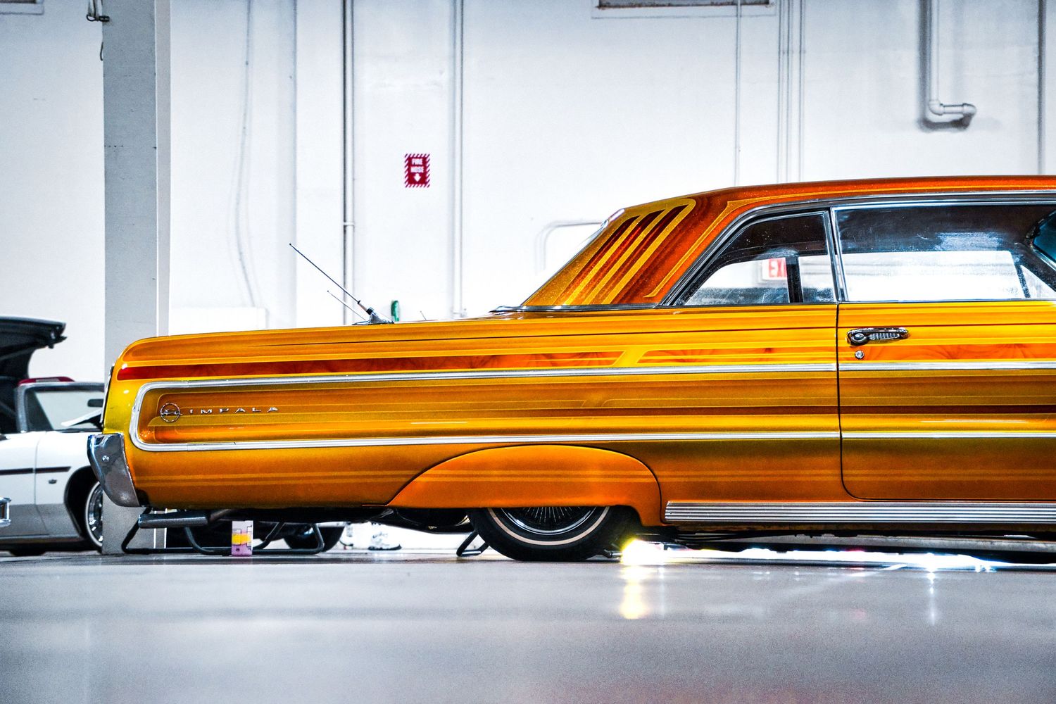 Custom lowrider car in metallic orange paint showcasing hydraulic suspension modifications.