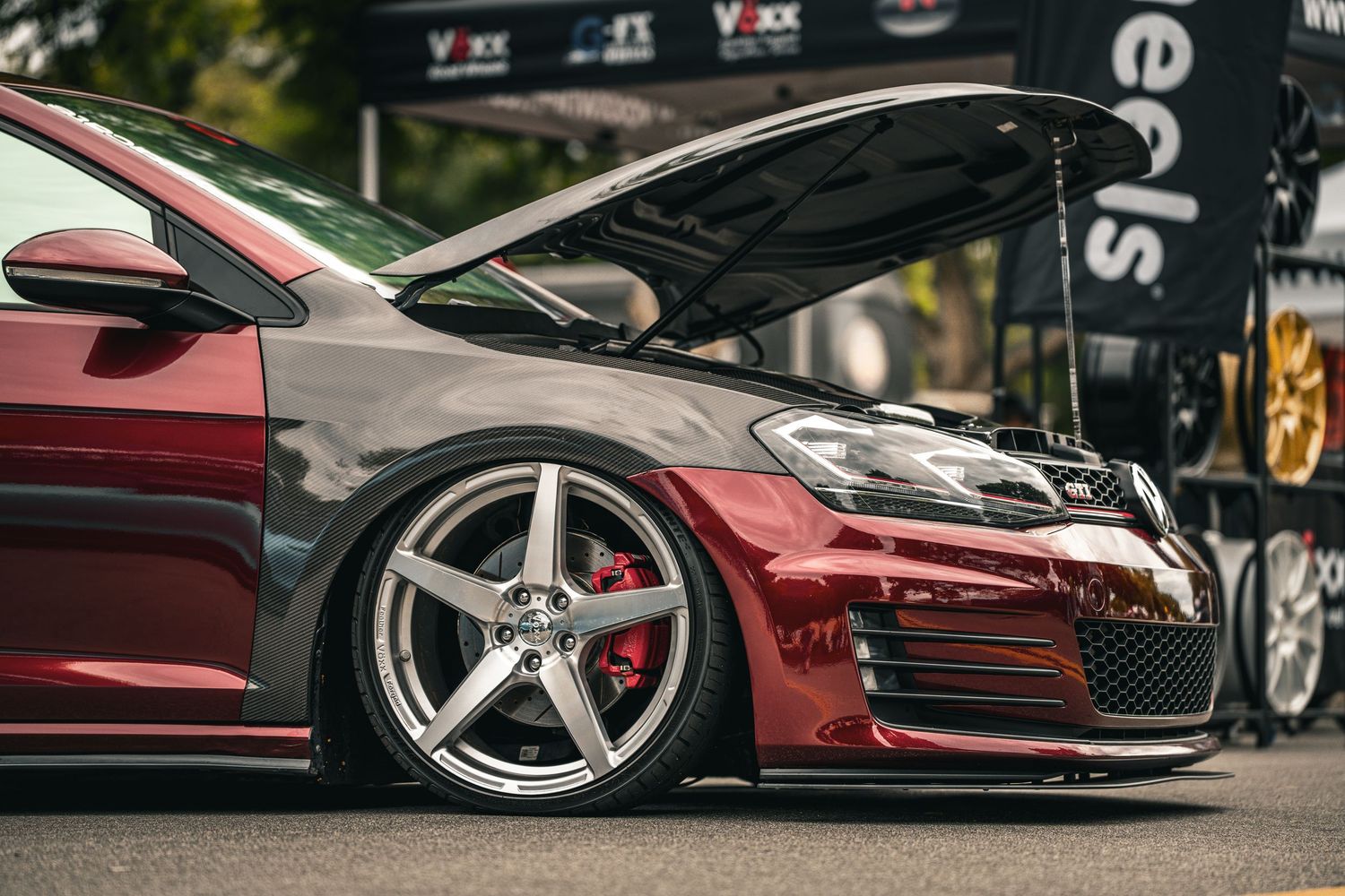 Low angle view of luxury sports cars with custom wheels at a car show.