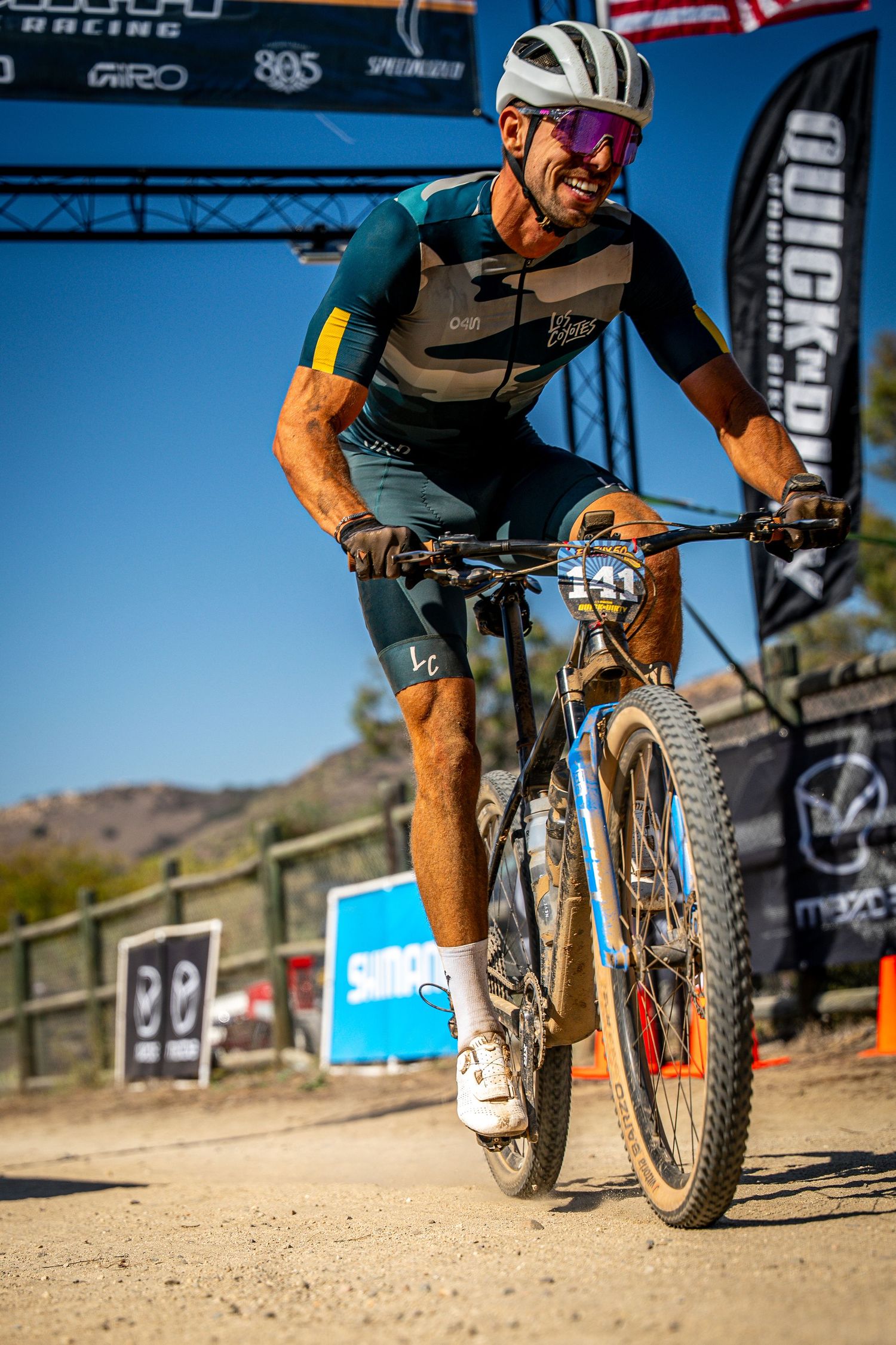 Mountain biker racing on a dusty trail during a competitive event.