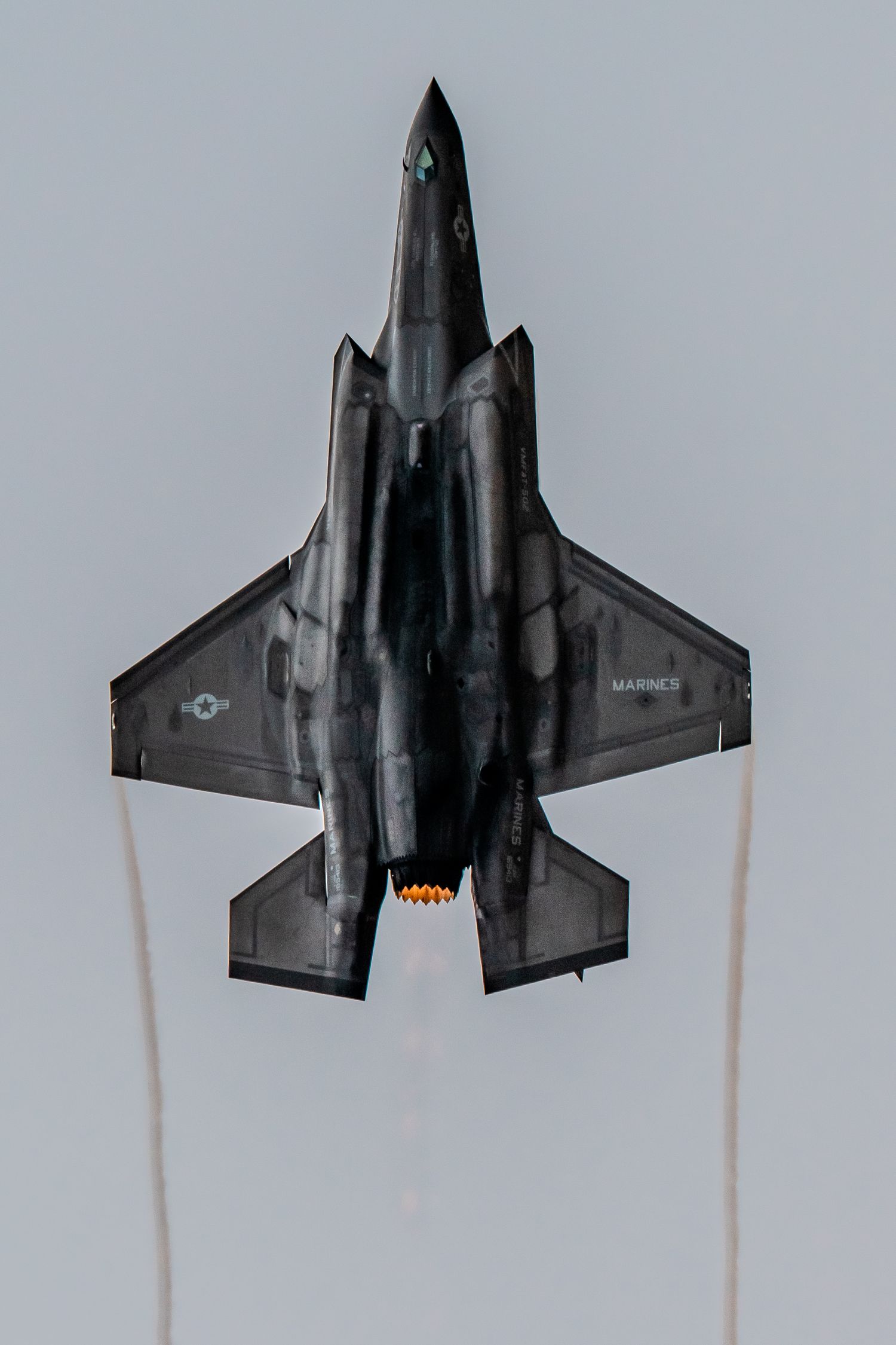 F-35 fighter jet performs aerial maneuvers against a cloudy sky background.
