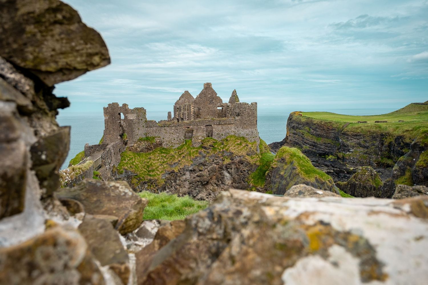 Ancient castle ruins perched dramatically on coastal cliffs overlooking the ocean.
