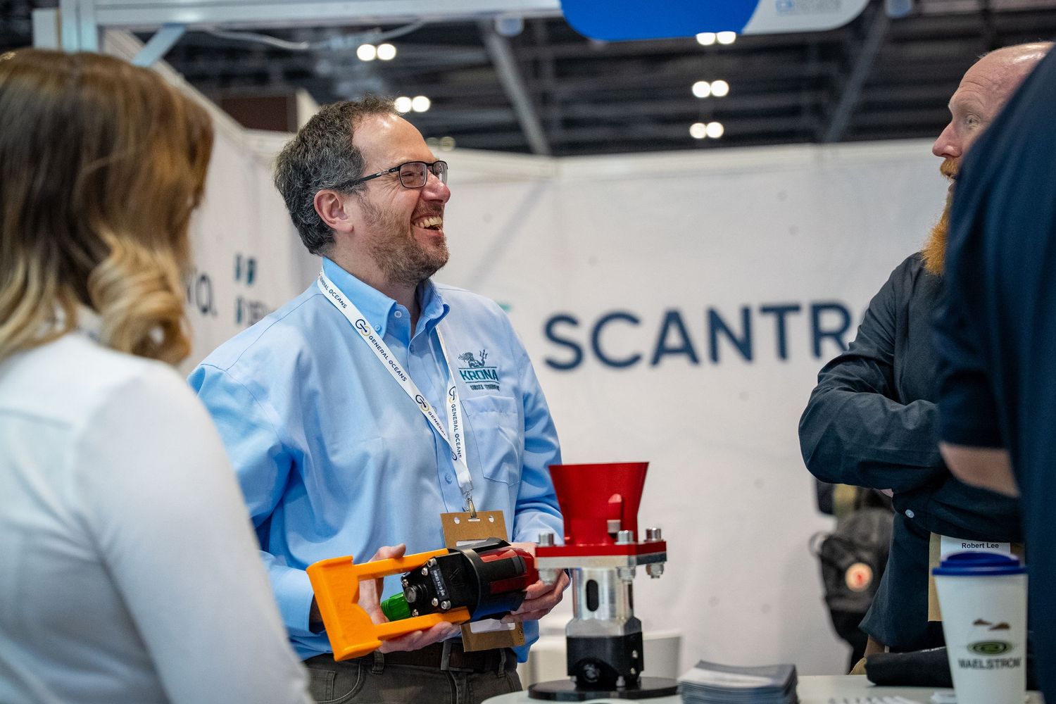 Man in blue shirt smiling at a trade show booth with Scantr branding, holding a product display.
