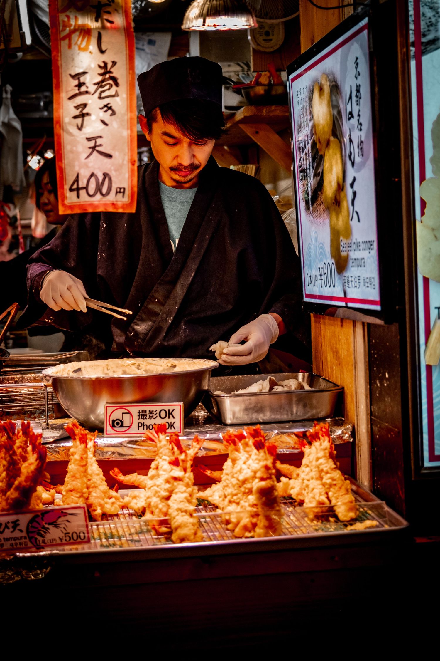 Food vendor preparing and displaying tempura at a Japanese street market stall.
