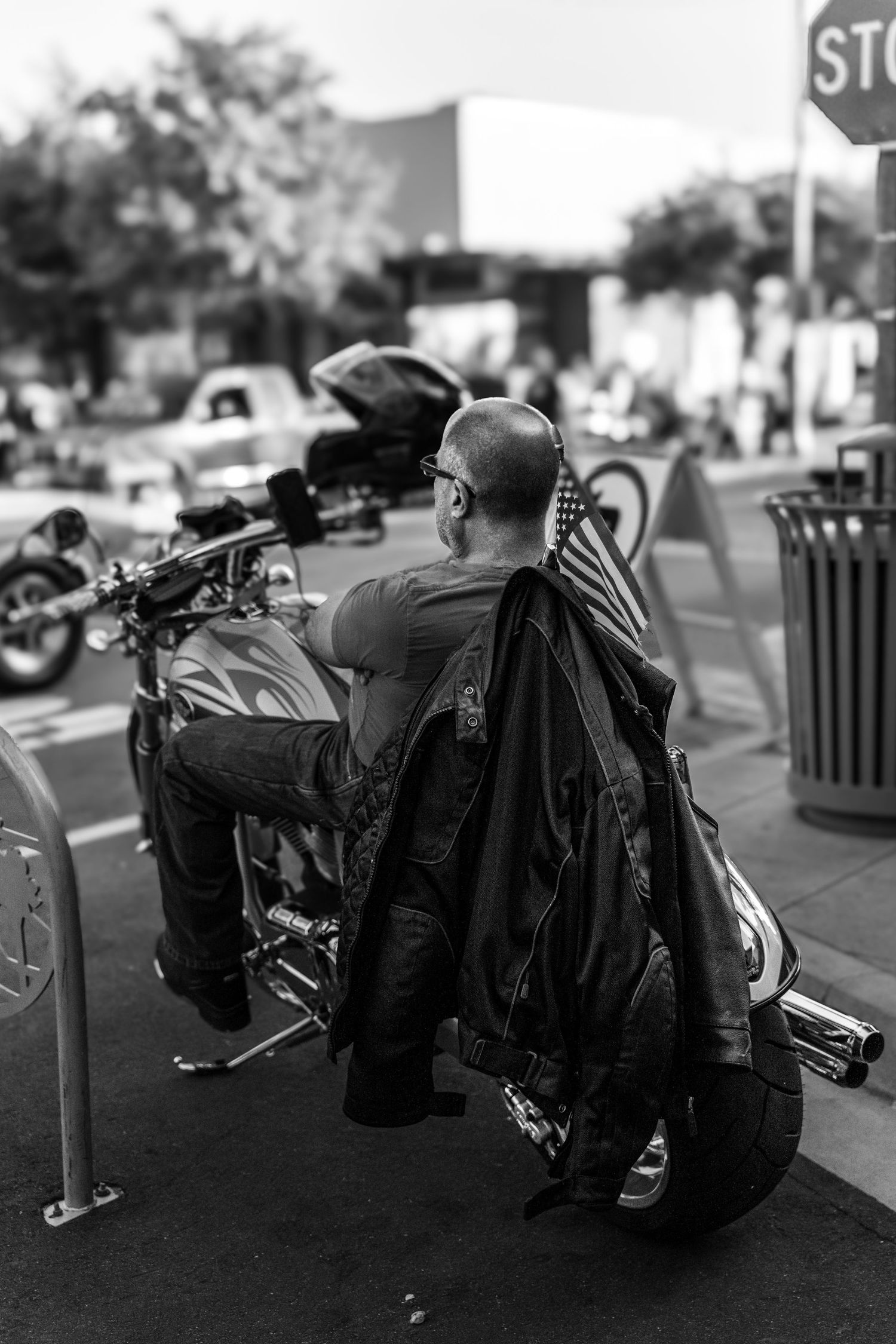 Motorcyclist with gear bags standing beside parked bikes on urban street.