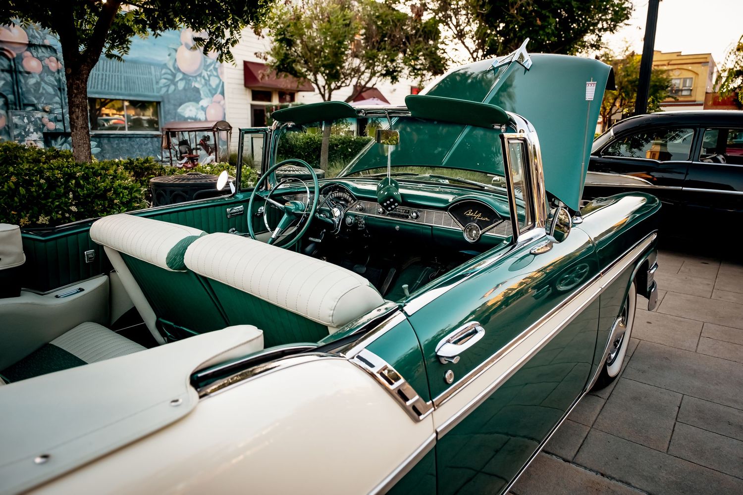Classic vintage car with chrome trim parked on a street in front of storefronts.