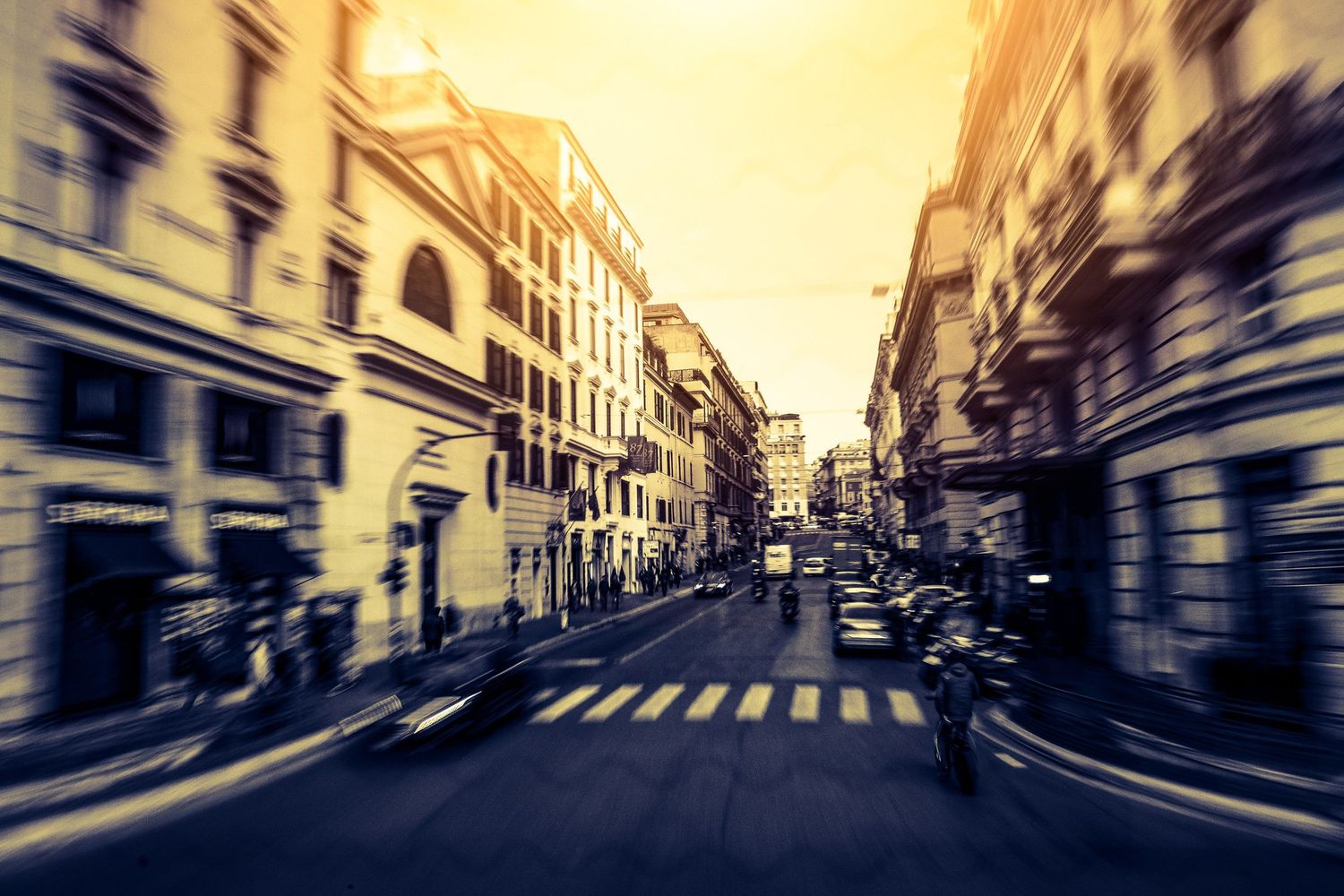 Urban street scene with motion blur effect and warm yellow tones.