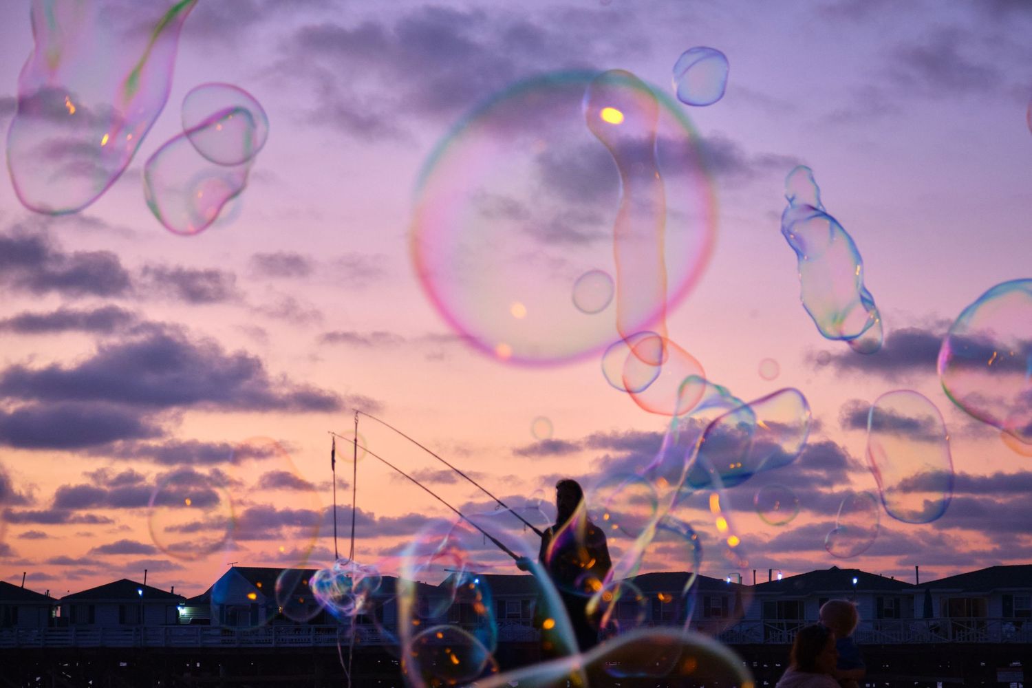 Colorful soap bubbles float against a purple sunset sky creating a magical atmosphere.
