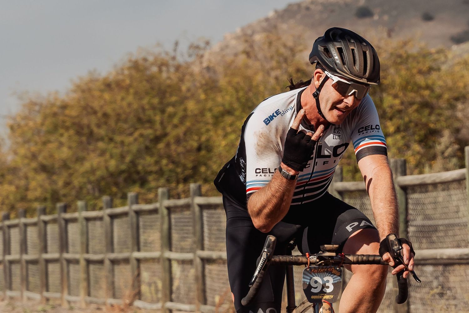 Cyclist in racing gear pedaling on a scenic mountain road during a sunny day.