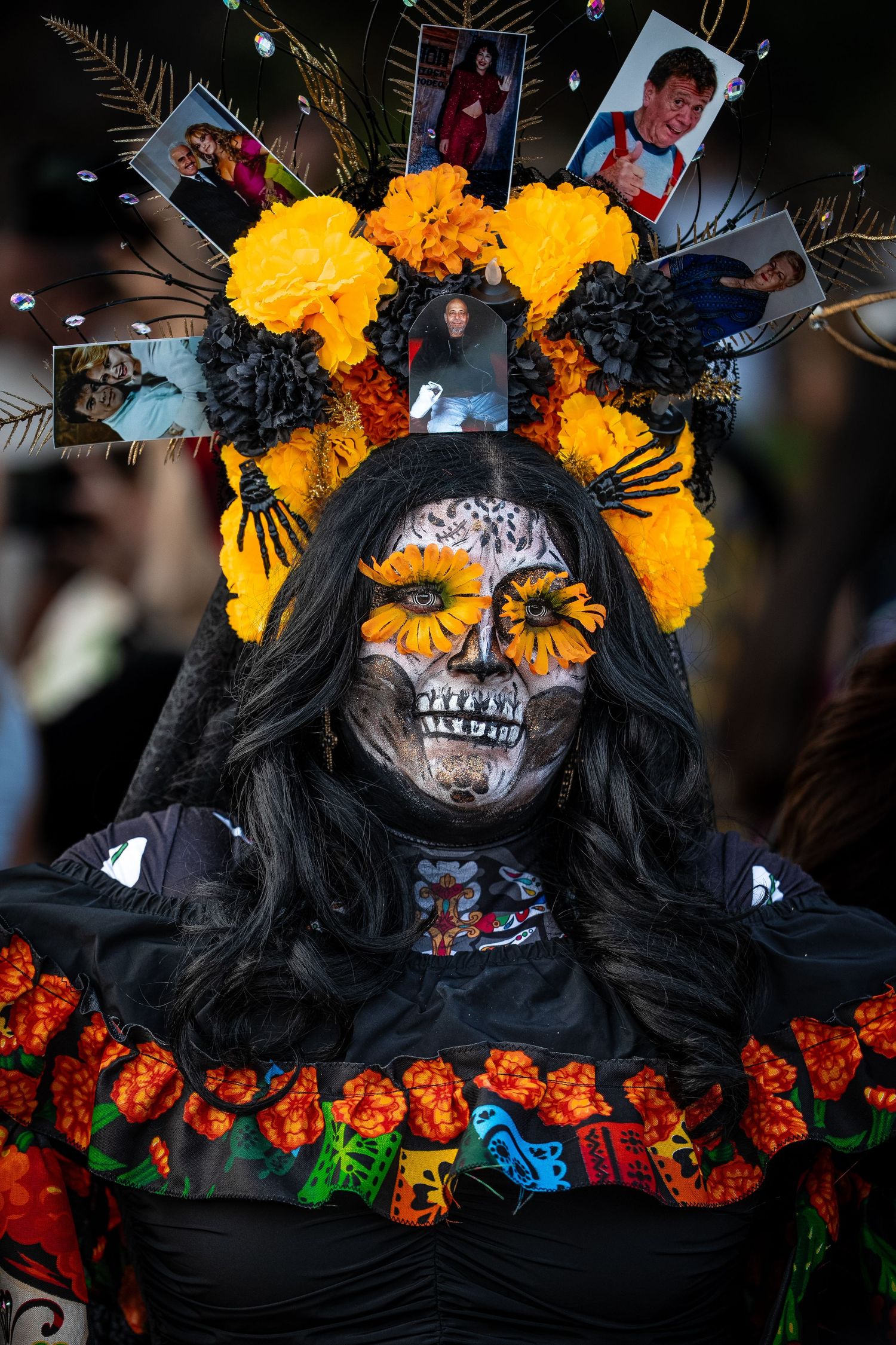 Sugar skull makeup with yellow marigold flowers and black hair against dark background.