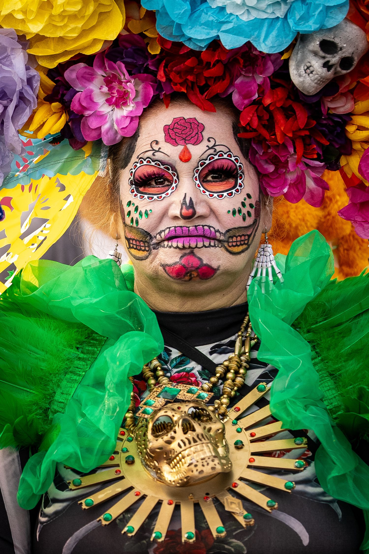 Day of the Dead performers wearing bright floral crowns and traditional sugar skull face paint with green costumes.