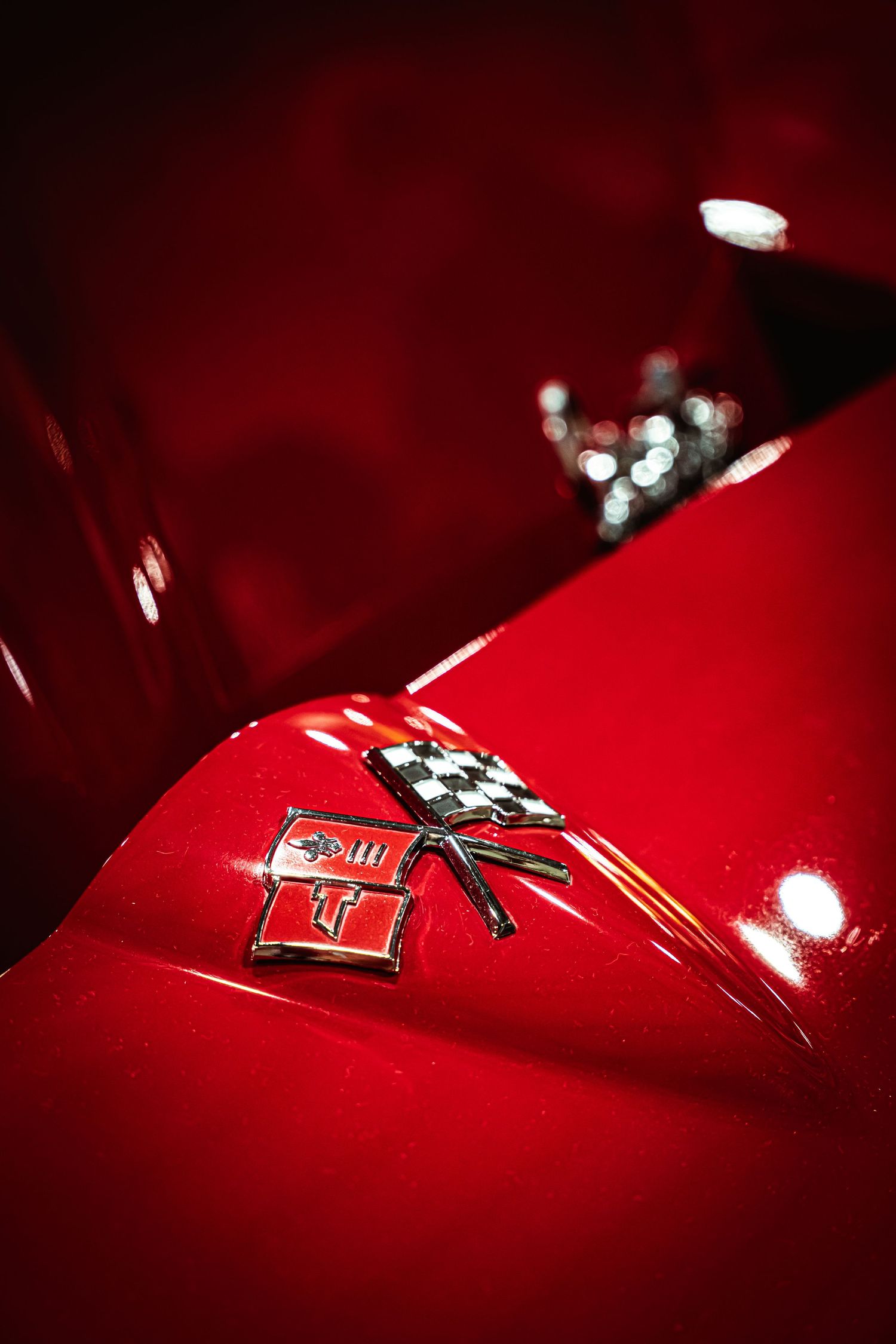 Close-up detail shot of a red sports car emblem with dramatic lighting.