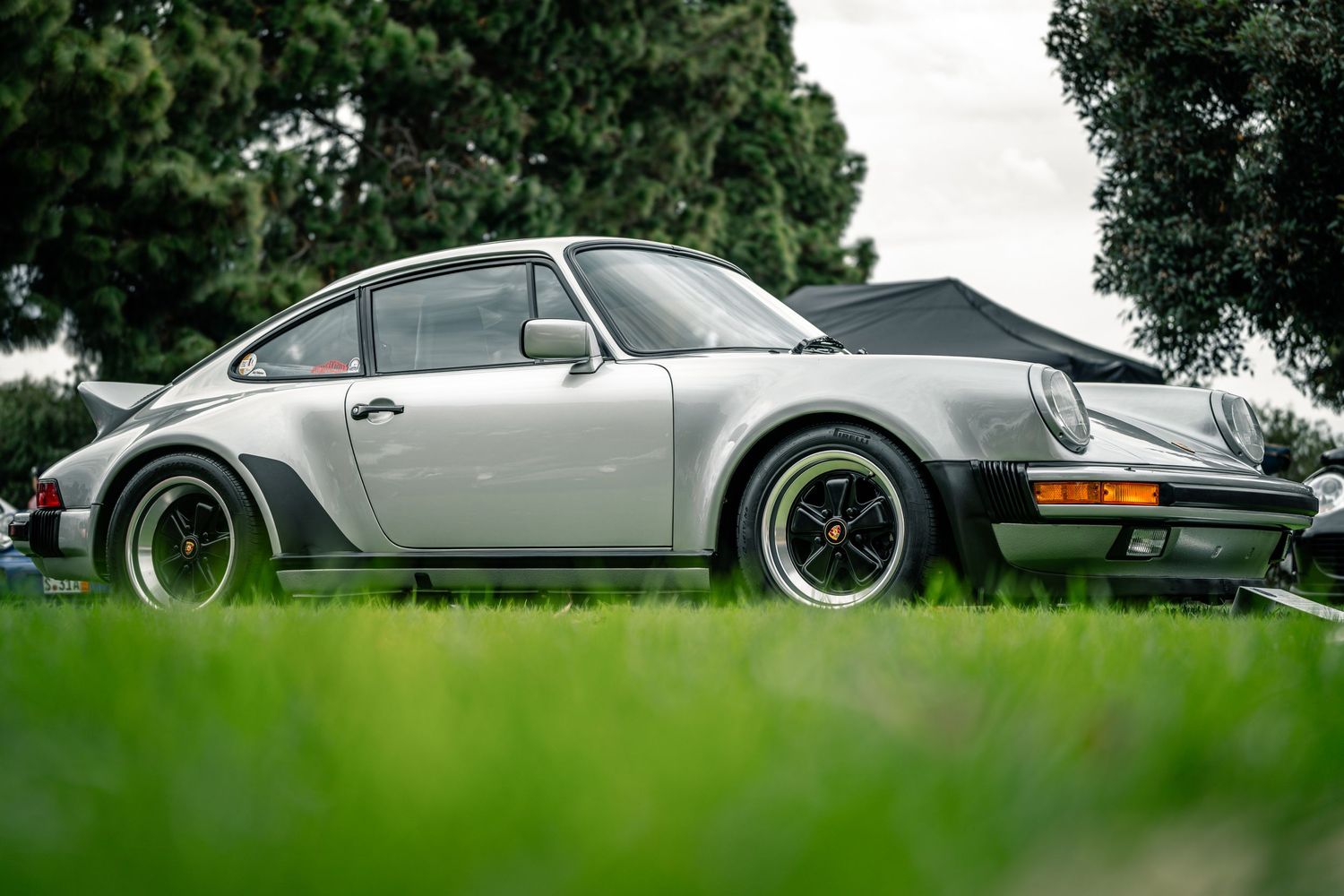 Row of classic sports cars displayed on manicured grass at automotive event.