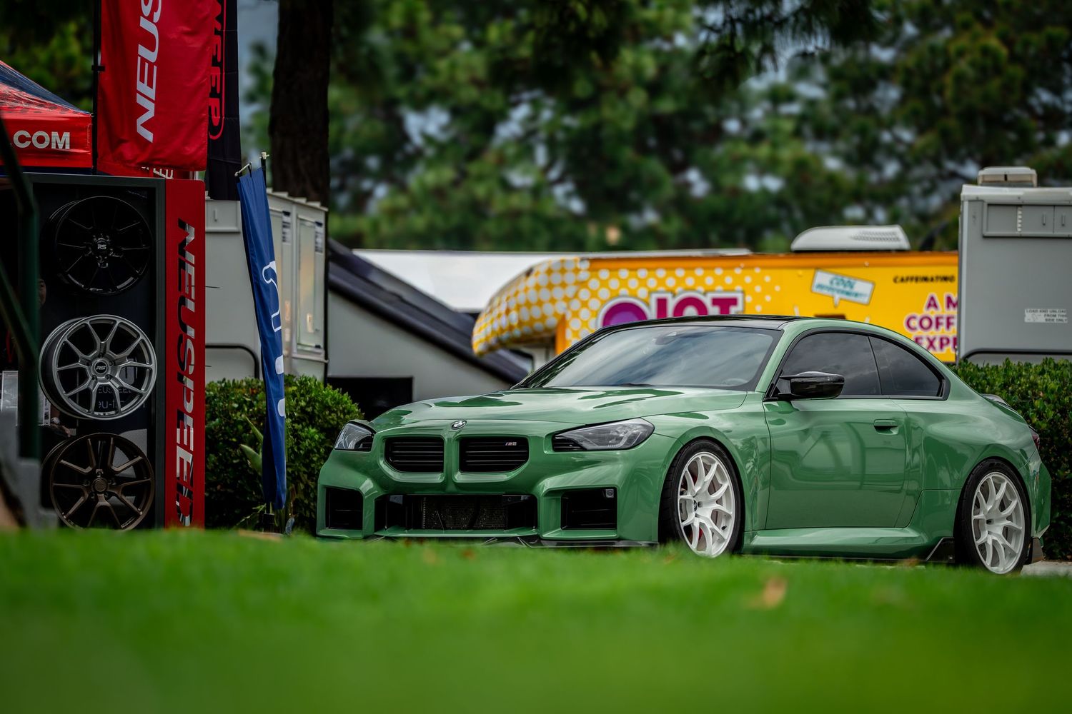 Row of luxury BMW vehicles displayed on grass at an outdoor car show.