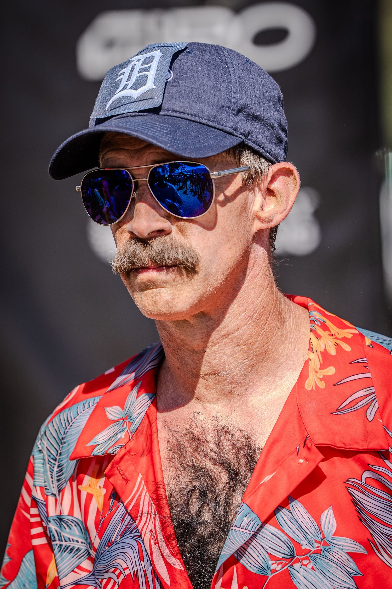 Man wearing sunglasses, baseball cap and red floral shirt in multiple profile shots.