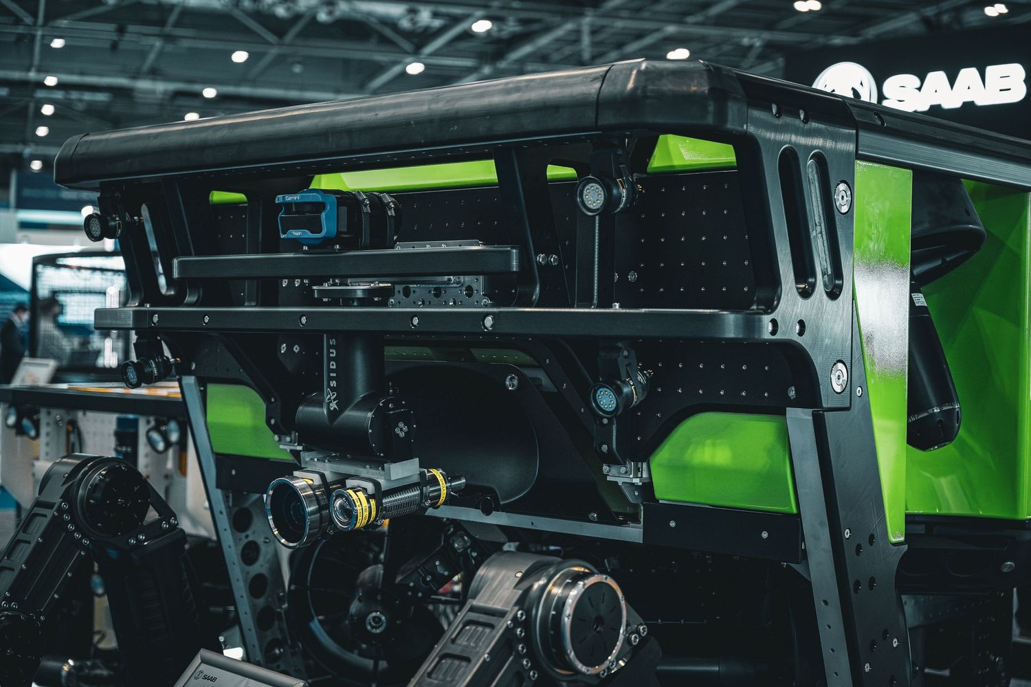 SAAB military vehicle with green and black design featuring advanced camera and sensor equipment on display.