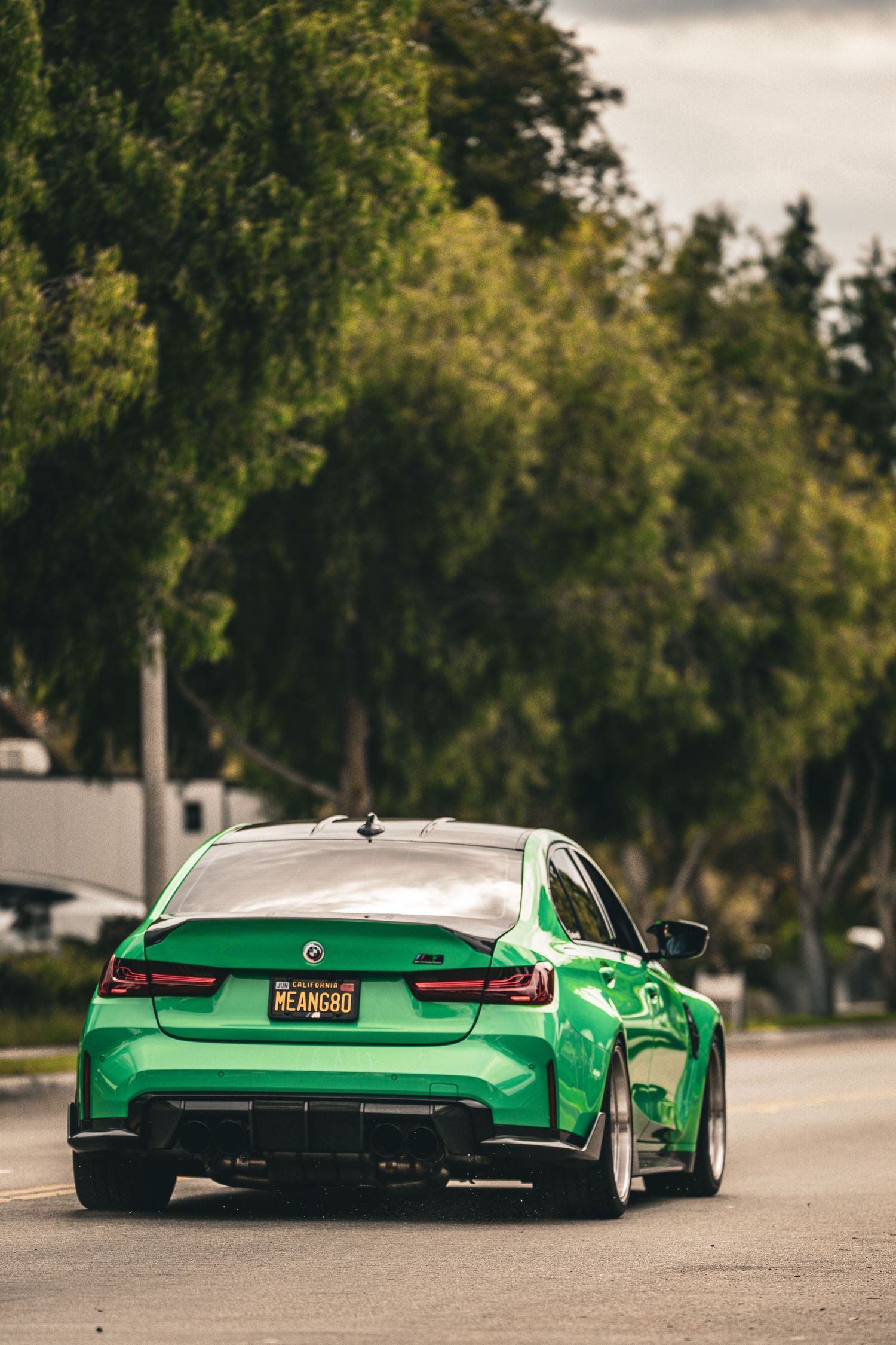 Bright green custom BMW M4 with lowered suspension and aftermarket modifications parked on a street.