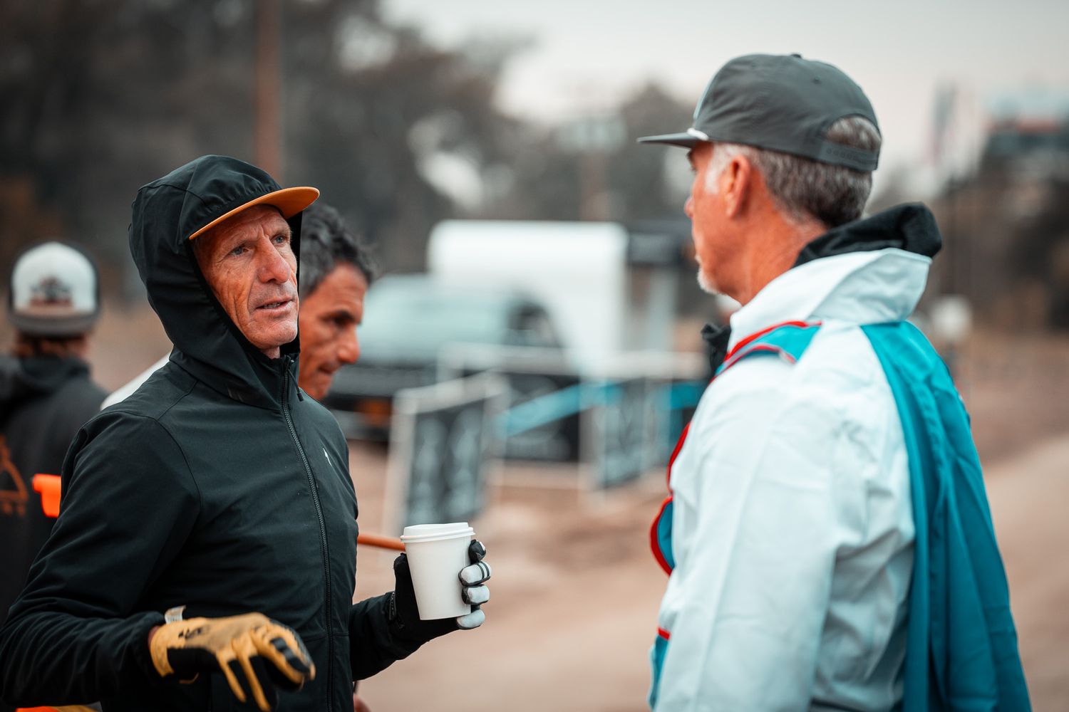 Two people in winter clothing having a conversation outdoors.