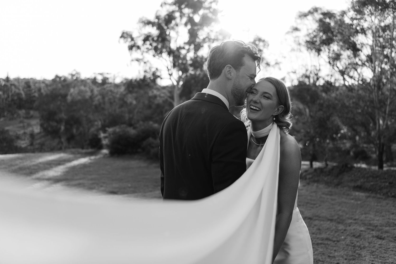 A romantic black and white wedding photo series showing intimate moments between a bride and groom in an outdoor setting.